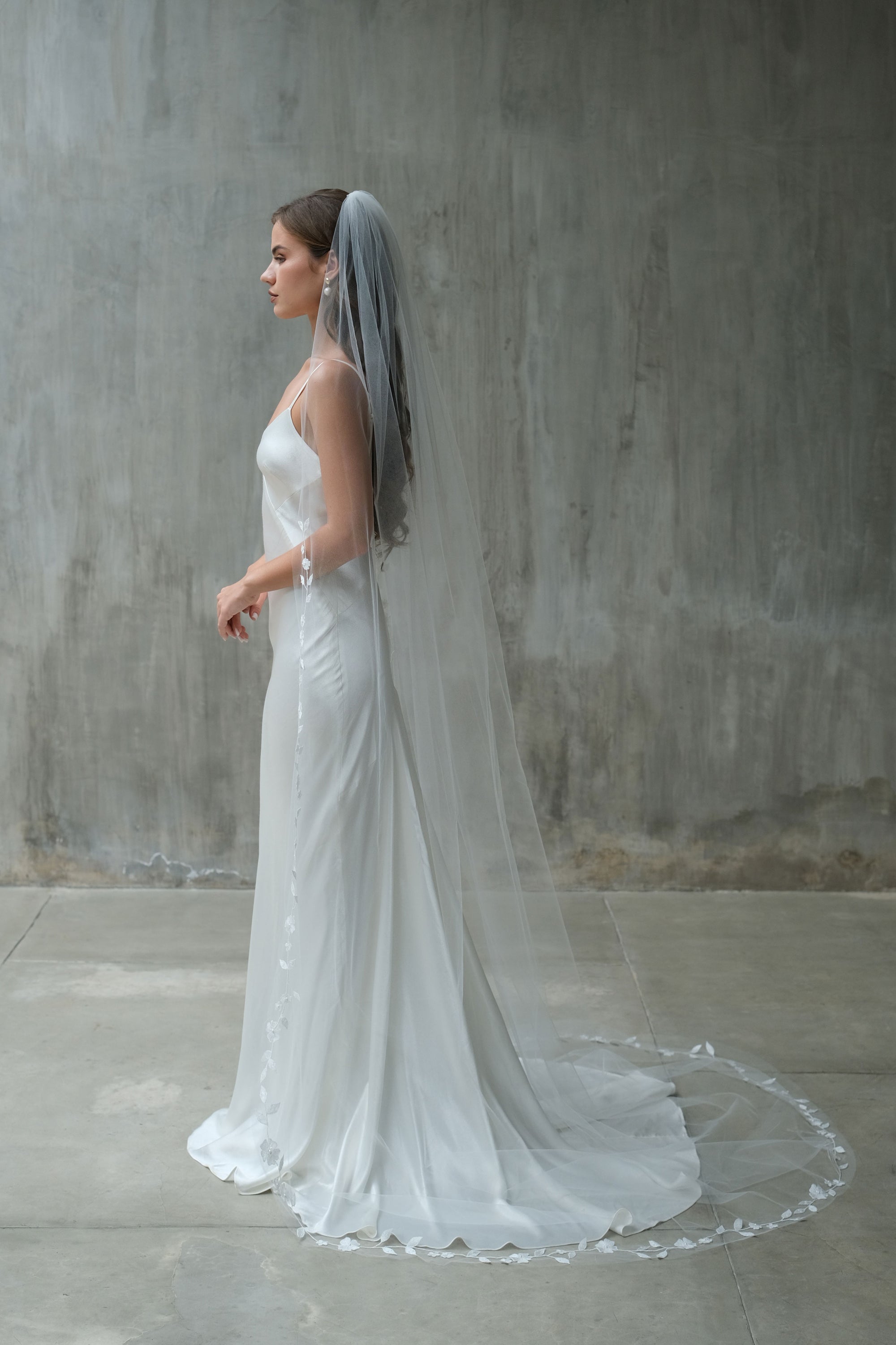Full length profile showing bride wearing long veil, gathered at the comb and embroidered along the edge with delicate floral vine