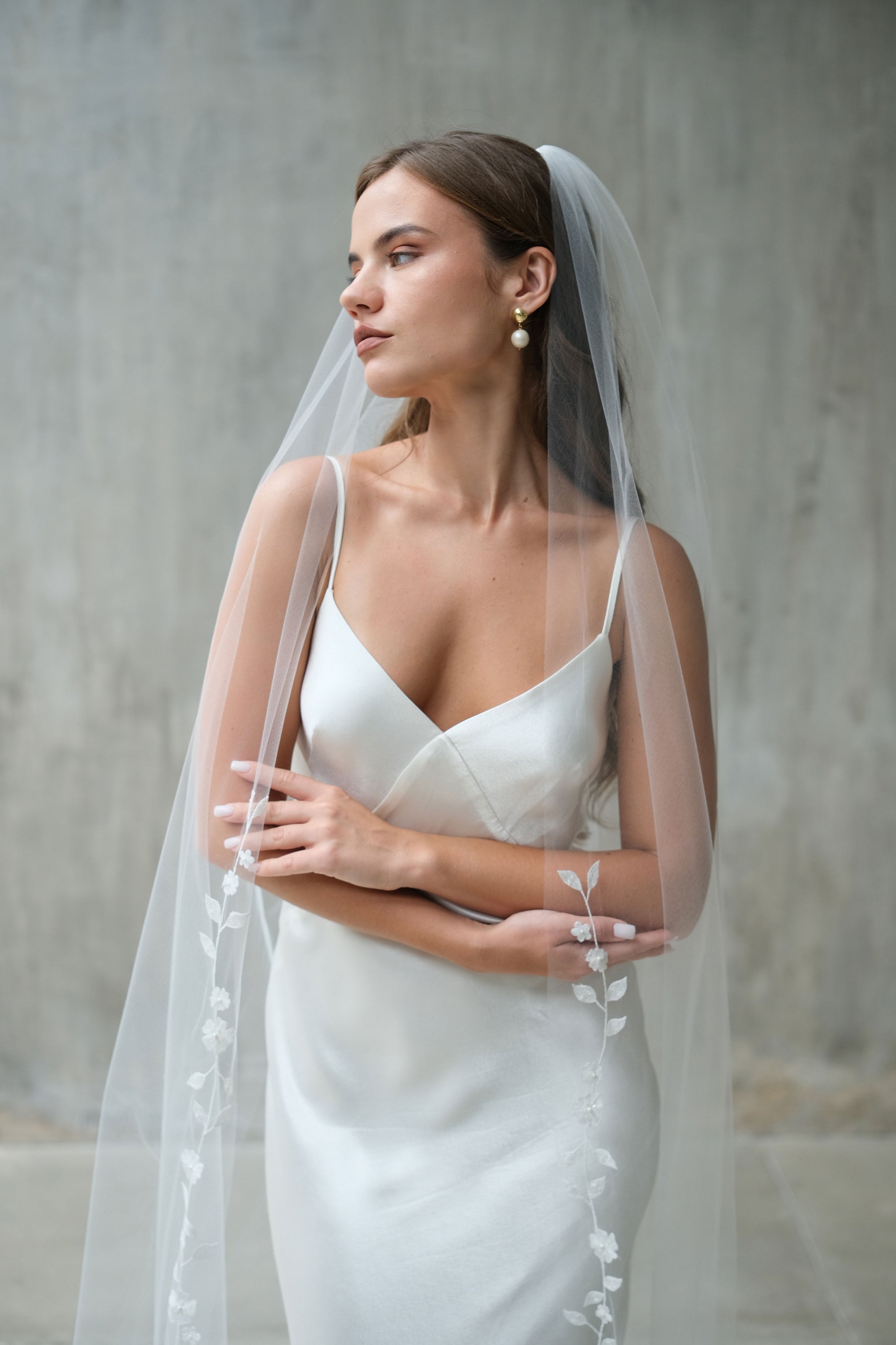 Bride wears single-tiered wedding veil, edged with floral embroidery featuring subtle bead detail