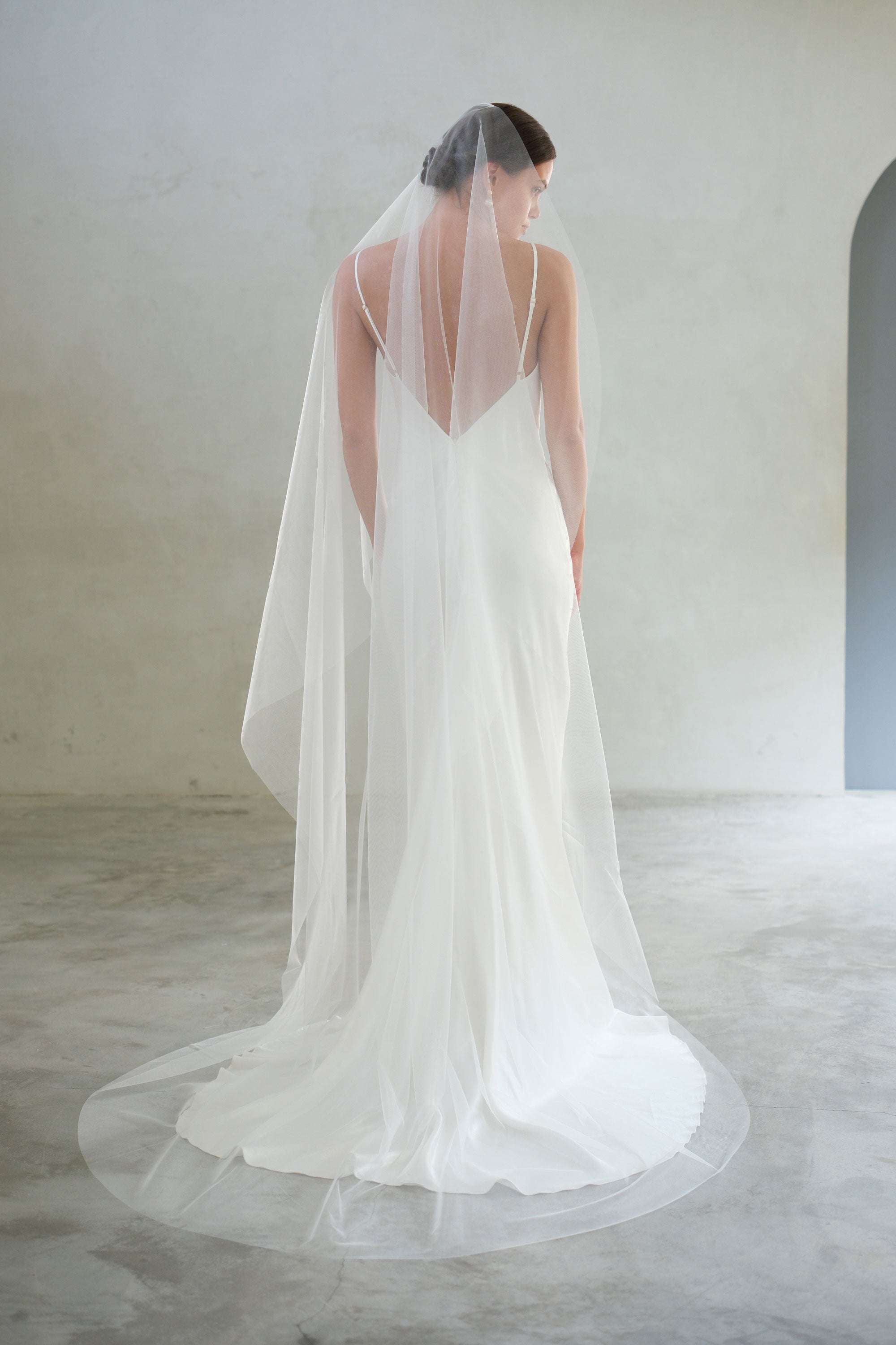 Full-length back view of bride wearing long mantilla-style minimalist bridal veil - shimmer fabric