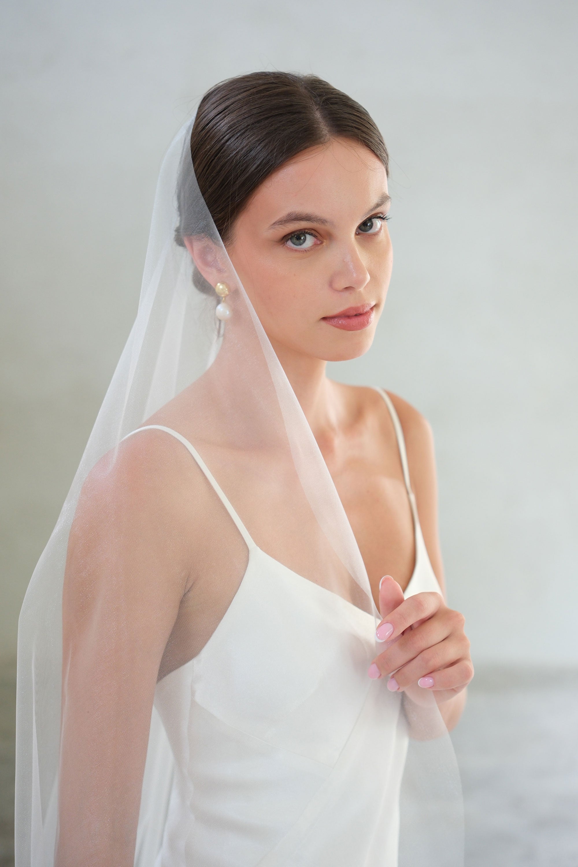 Head and shoulders front view of bride wearing mantilla-style plain bridal veil.