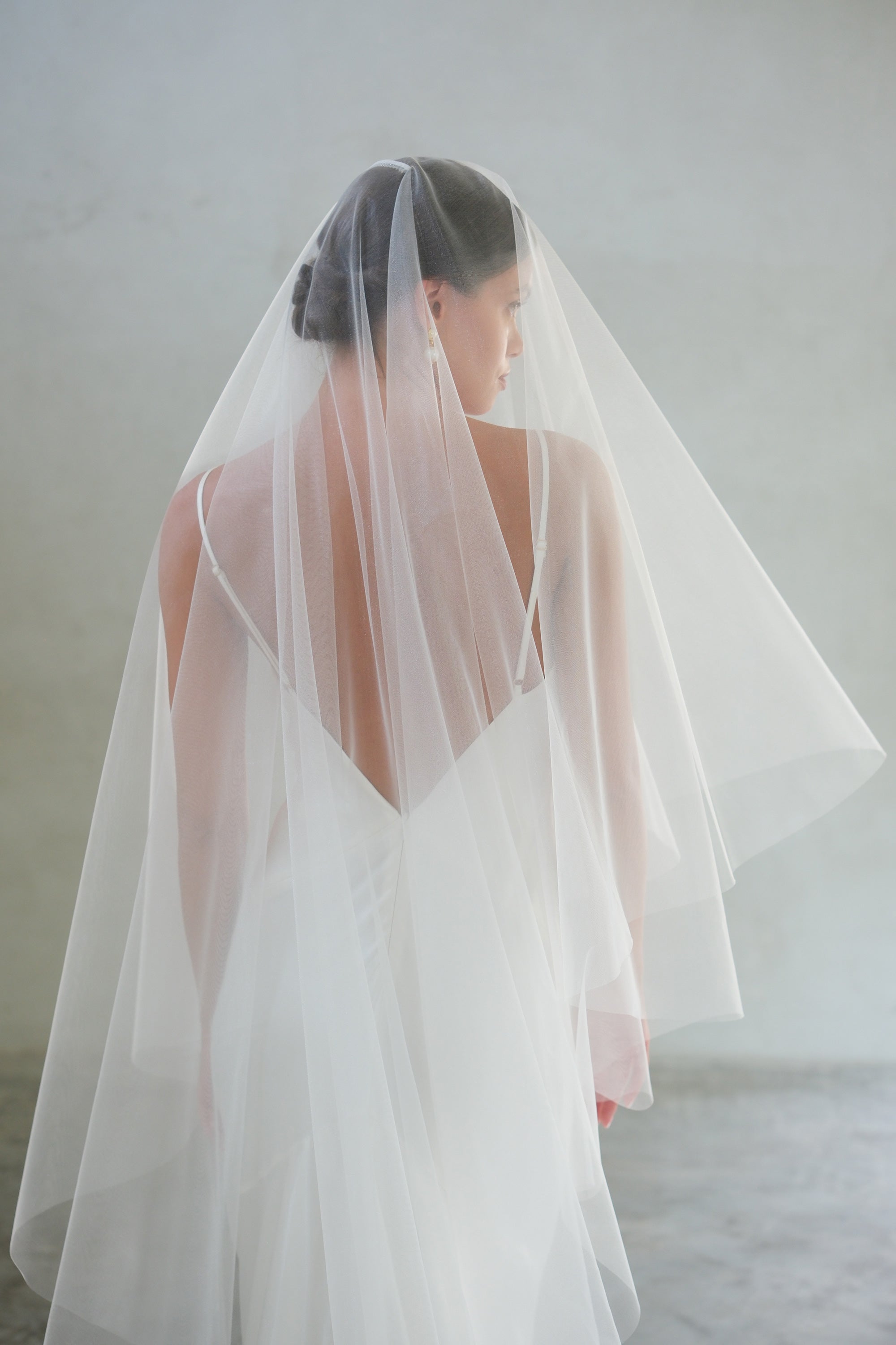 Half length shot showing back view of bride wearing two tier, shimmer tulle wedding veil - blusher down