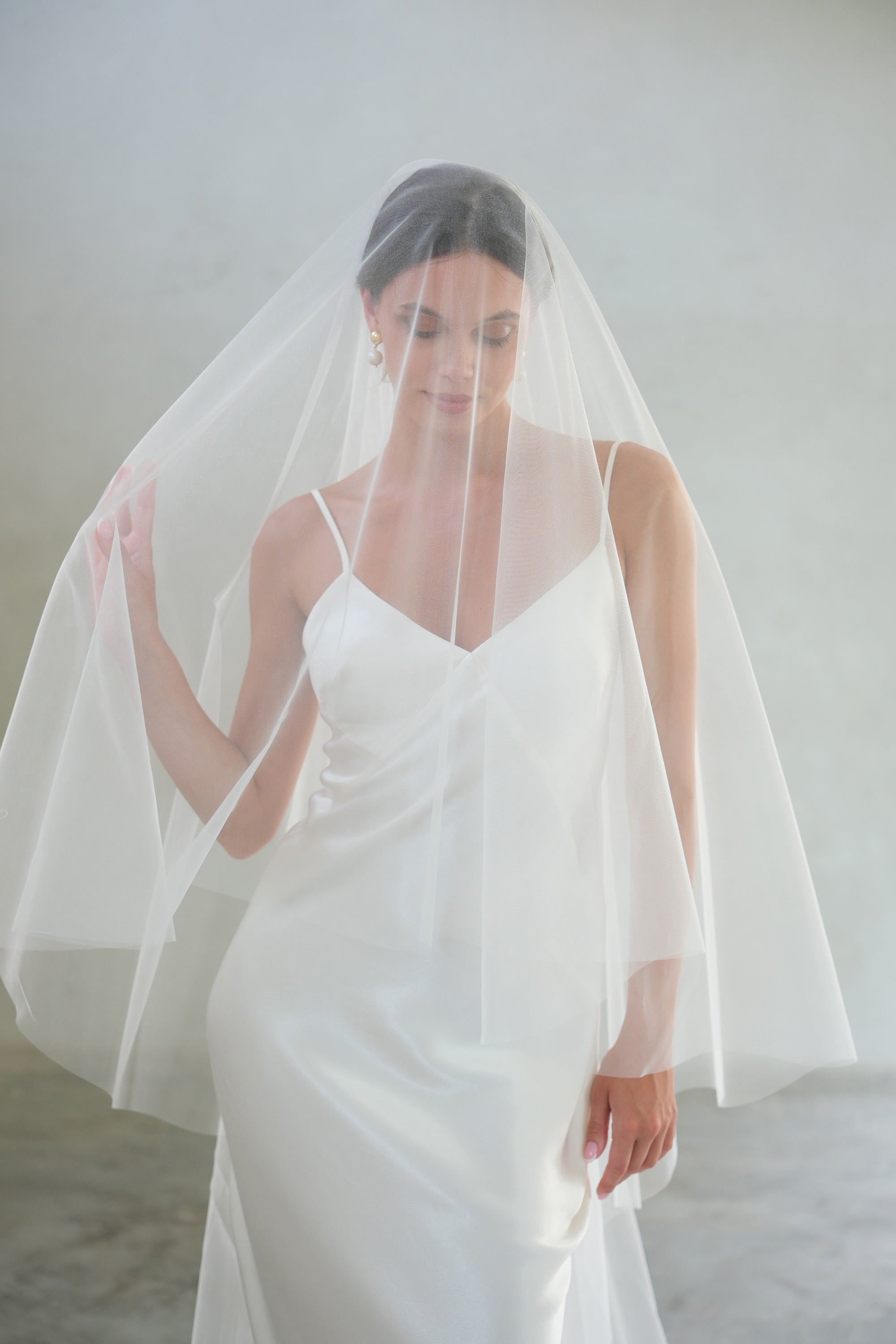 Half length front-facing shot of bride wearing ellie plain (unadorned) shimmer tulle veil, blusher down