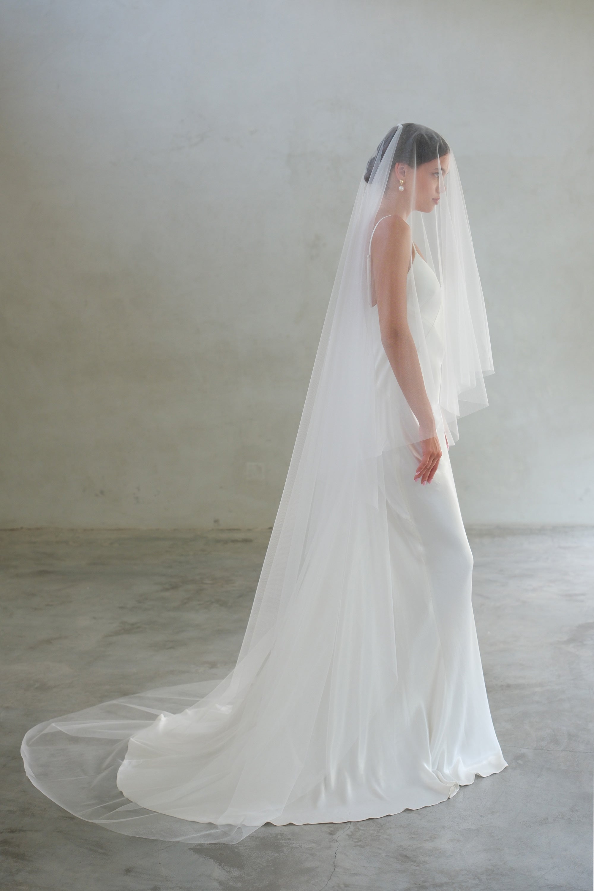 Full length profile of bride wearing long, two-tier wedding veil. shimmer tulle, blusher down.