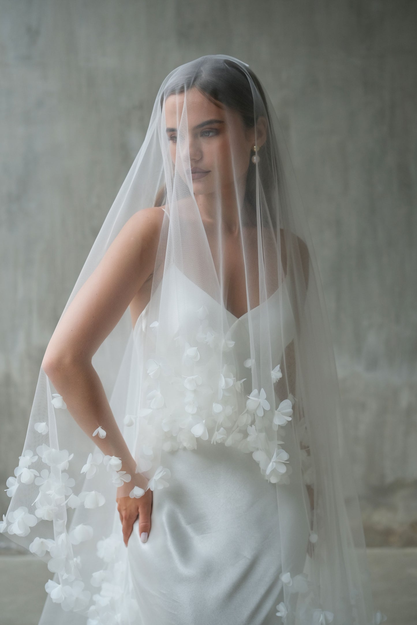 Front facing bride wearing drop veil embellished with fabric flowers, showing blusher down