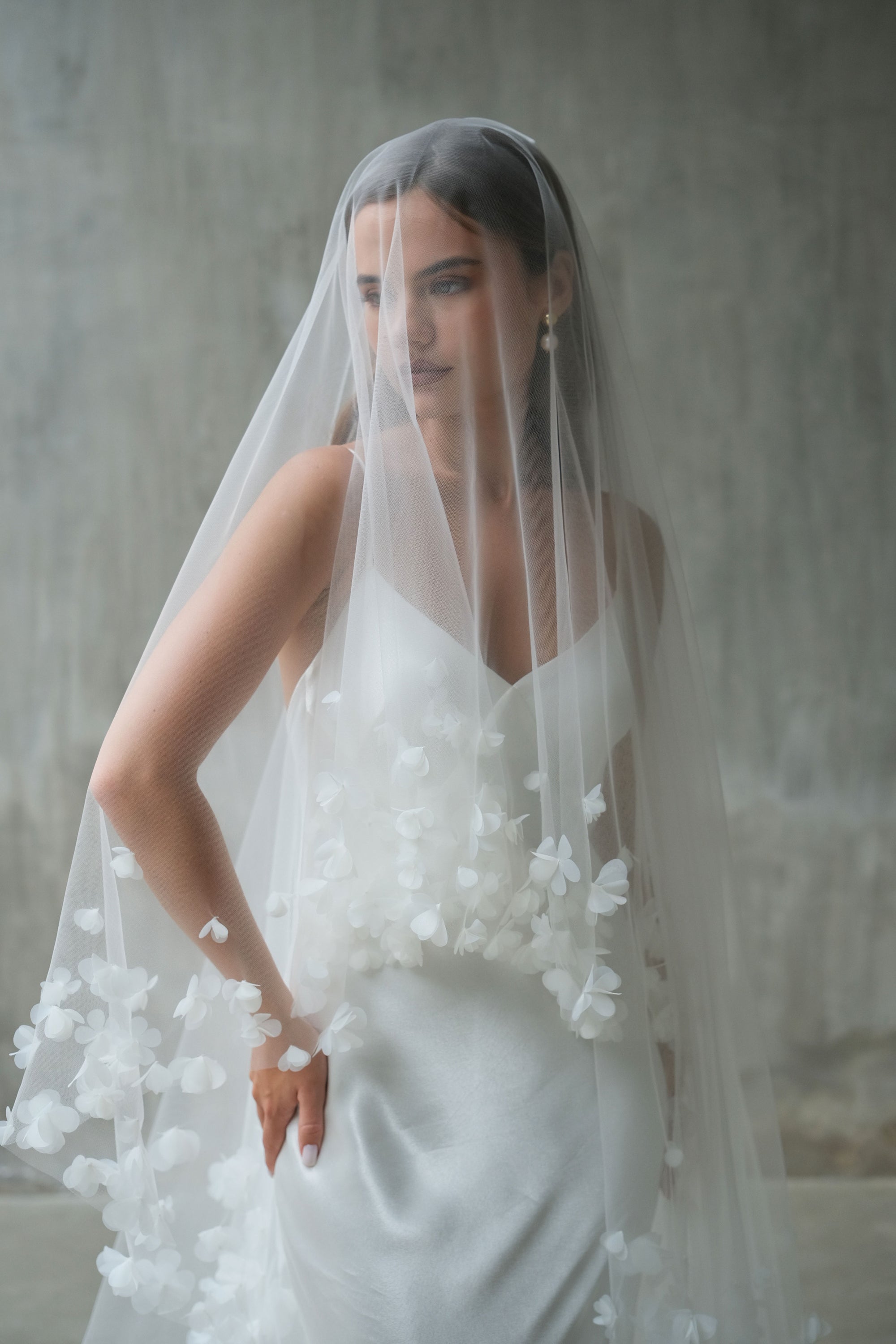 Front facing bride wearing drop veil embellished with fabric flowers, showing blusher down
