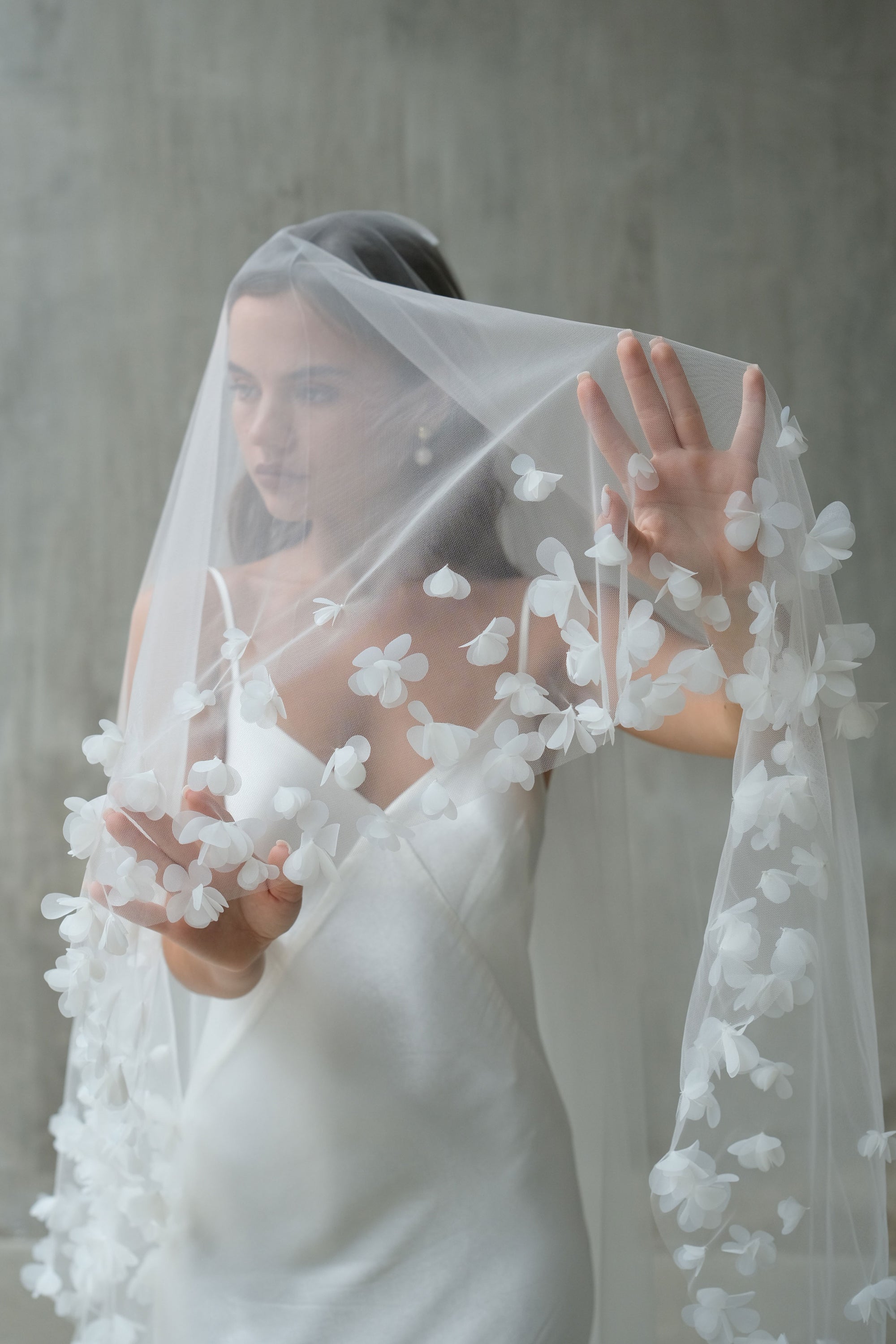 Bride holds veil to show floral embellishment on edges of blusher