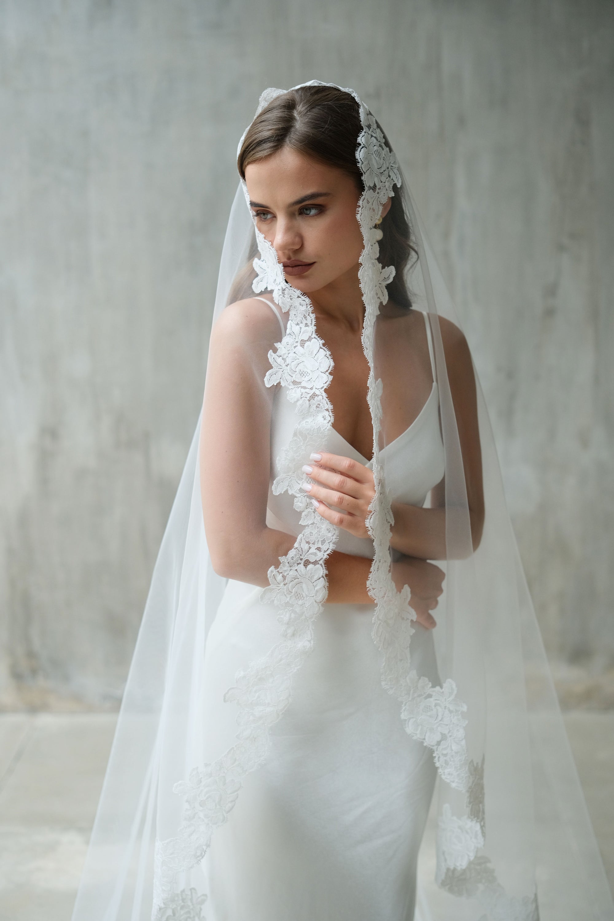A bride wearing one-tier mantilla lace edge long wedding veil