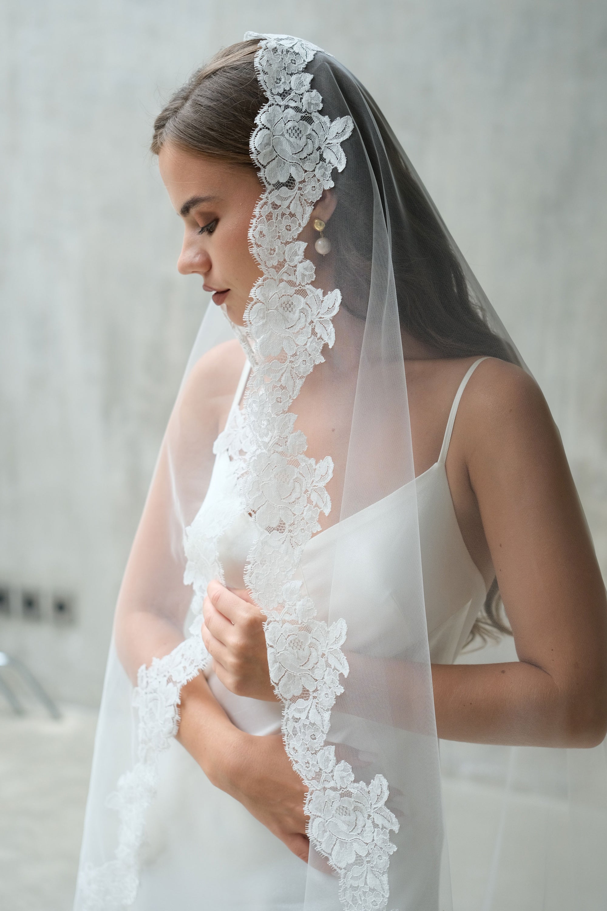 Side profile of a bride wearing a white lace wedding veil 