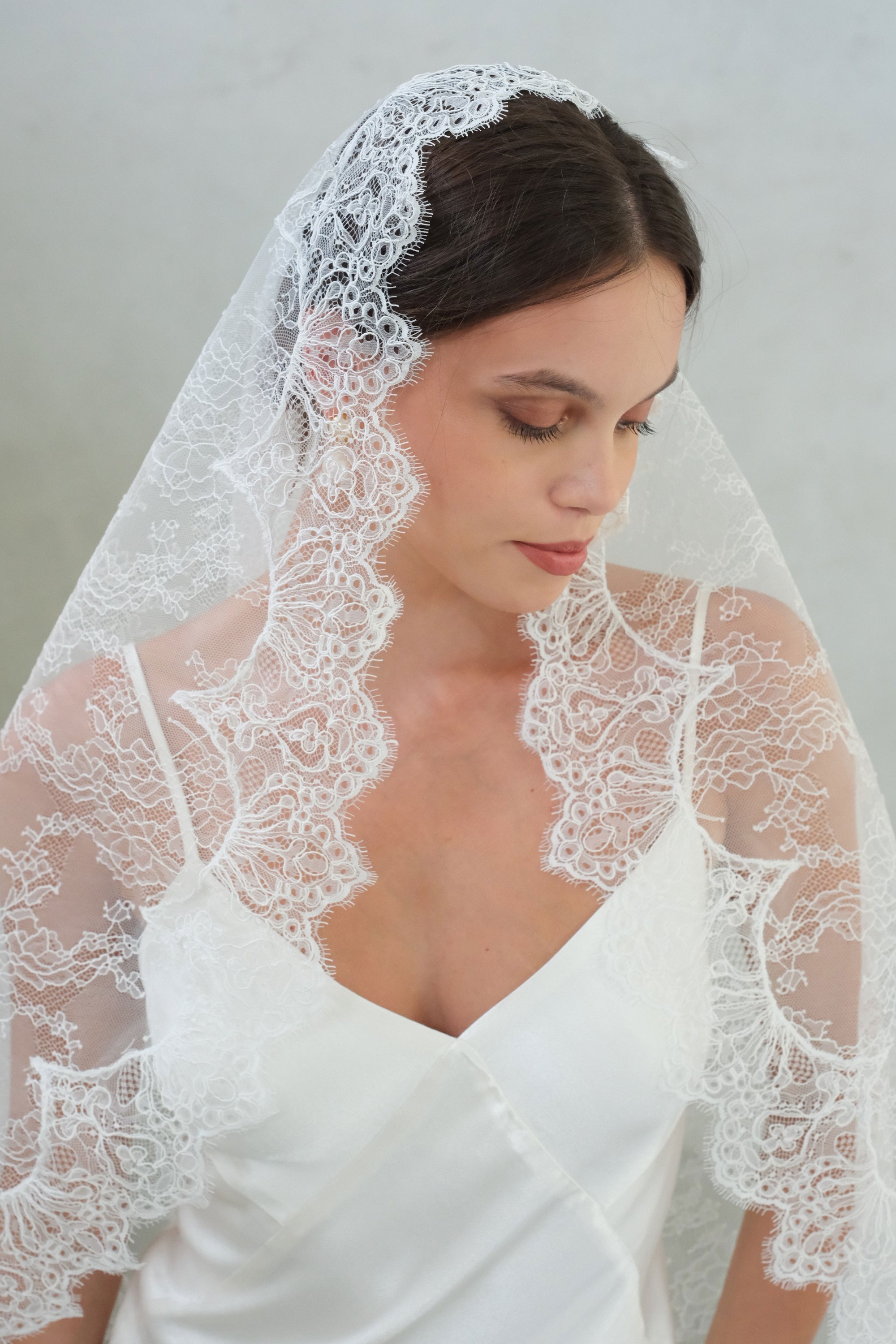 Head and shoulders detail of full sheer lace mantilla wedding veil and pretty scalloped edging