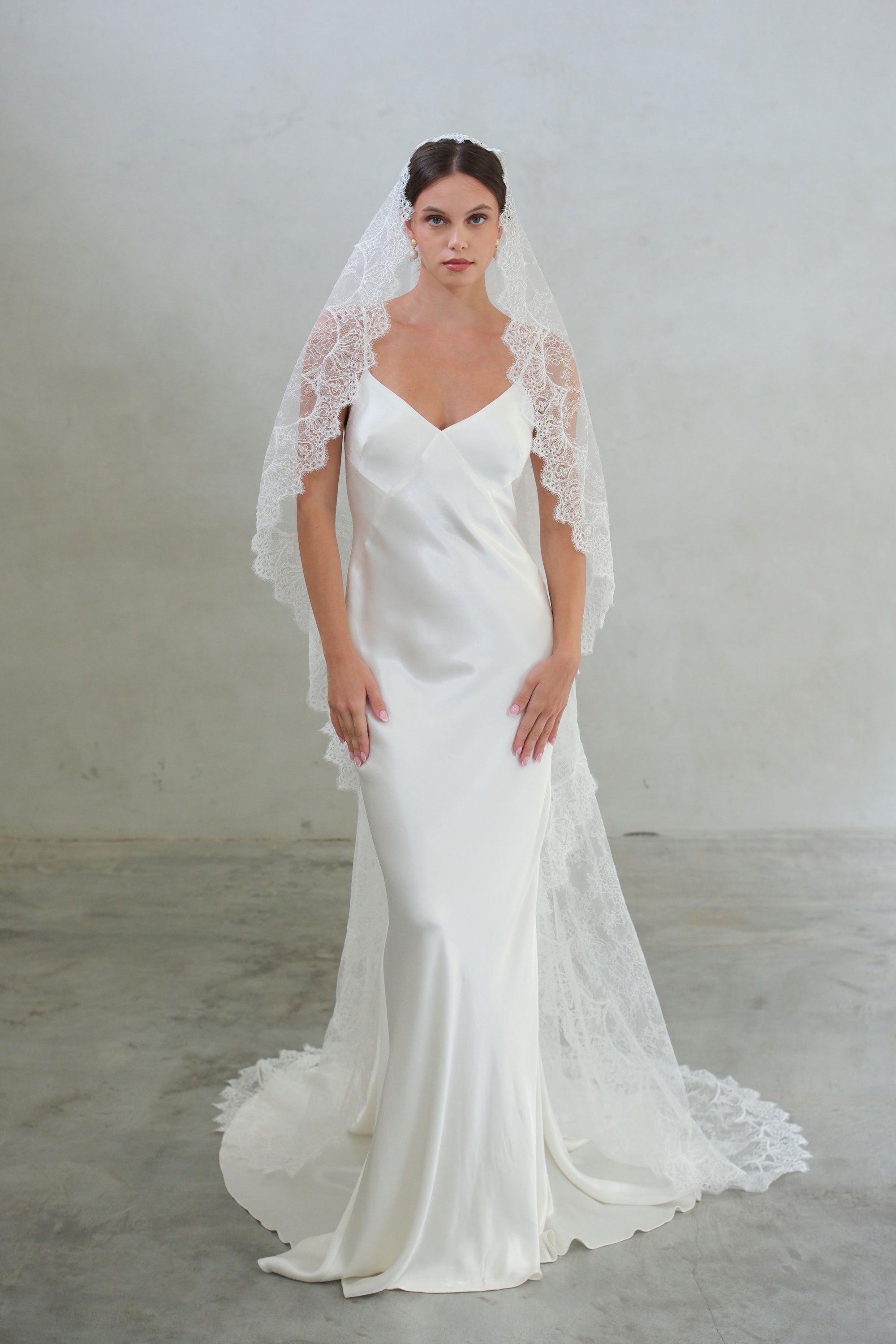 Full length front facing bride wears long, soft sheer lace mantilla veil edged with lace scalloping