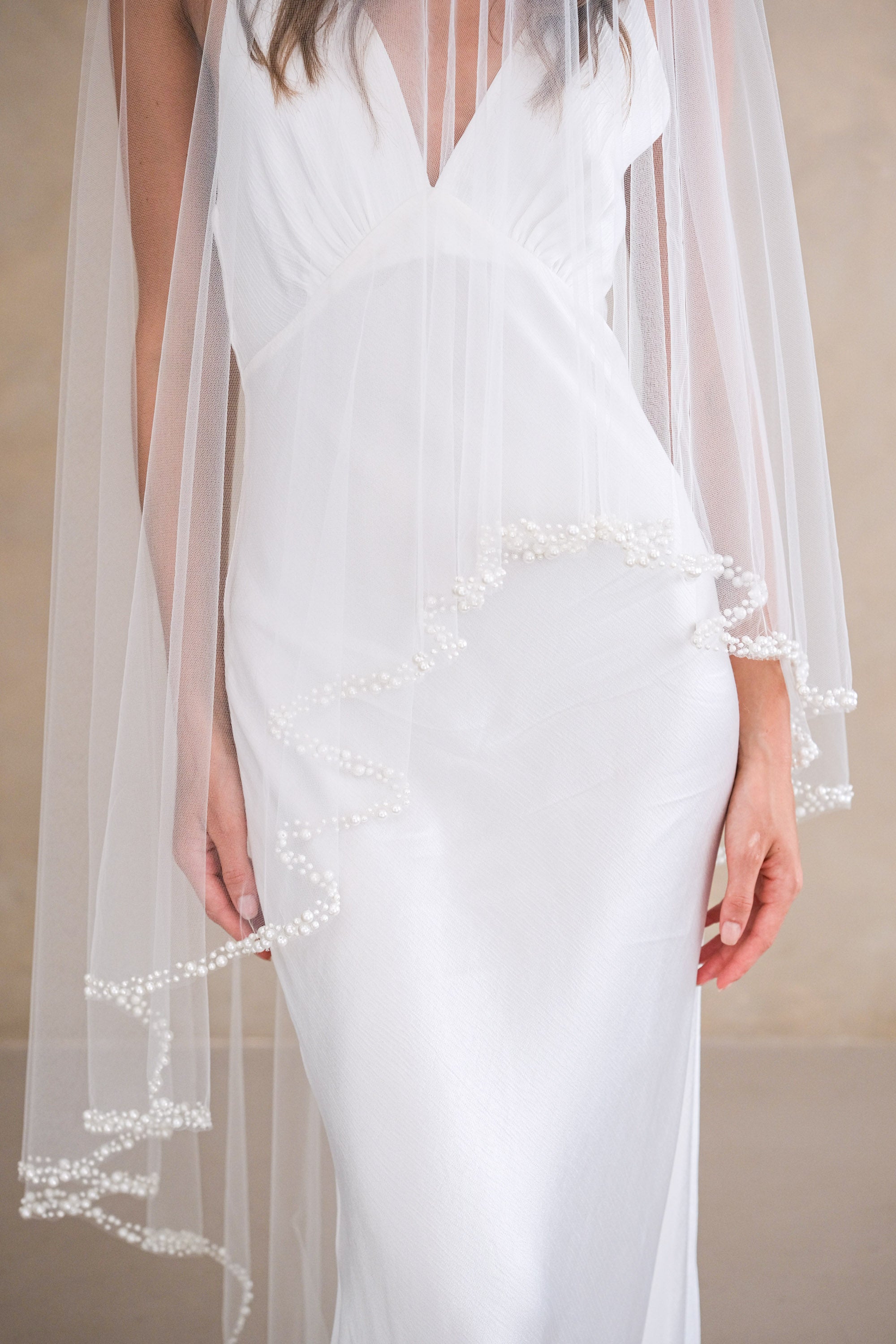 Model wears a pearl wedding veil, drop veil with pearls.