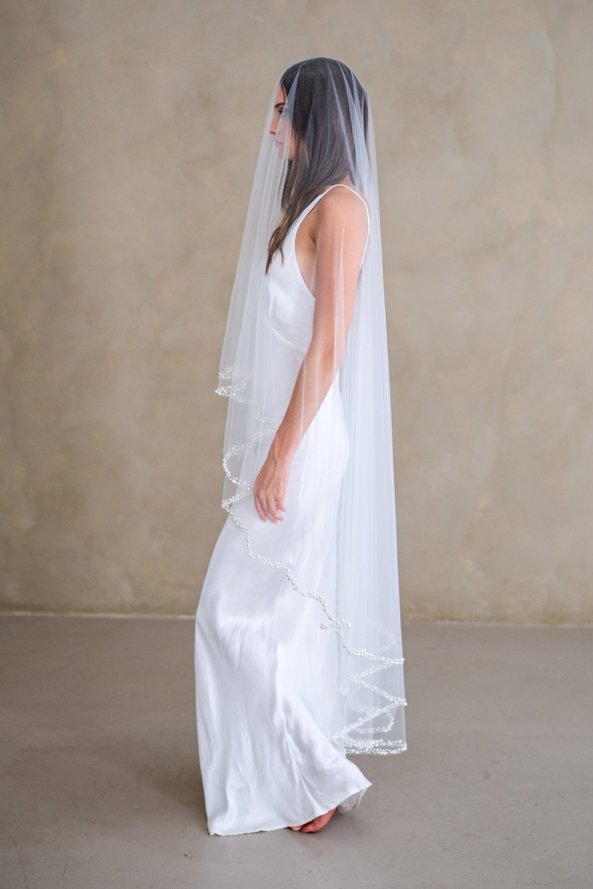 Model wears a pearl wedding veil, drop veil with pearls.