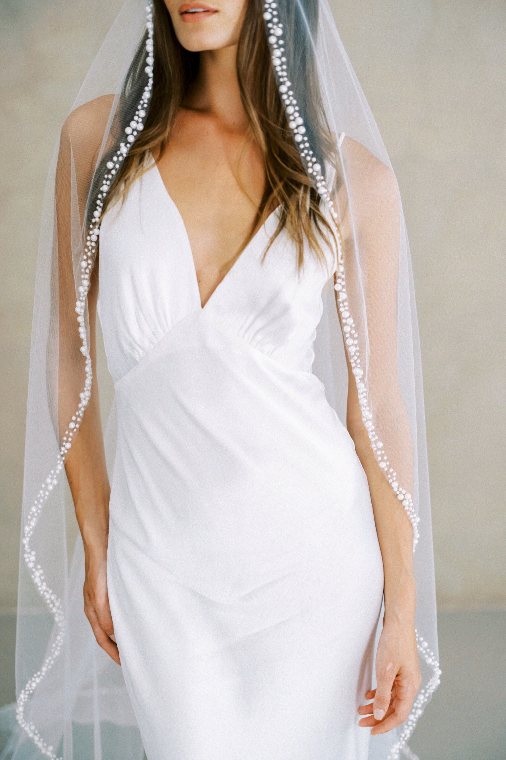 Model wears a pearl wedding veil, one tier veil with pearls.