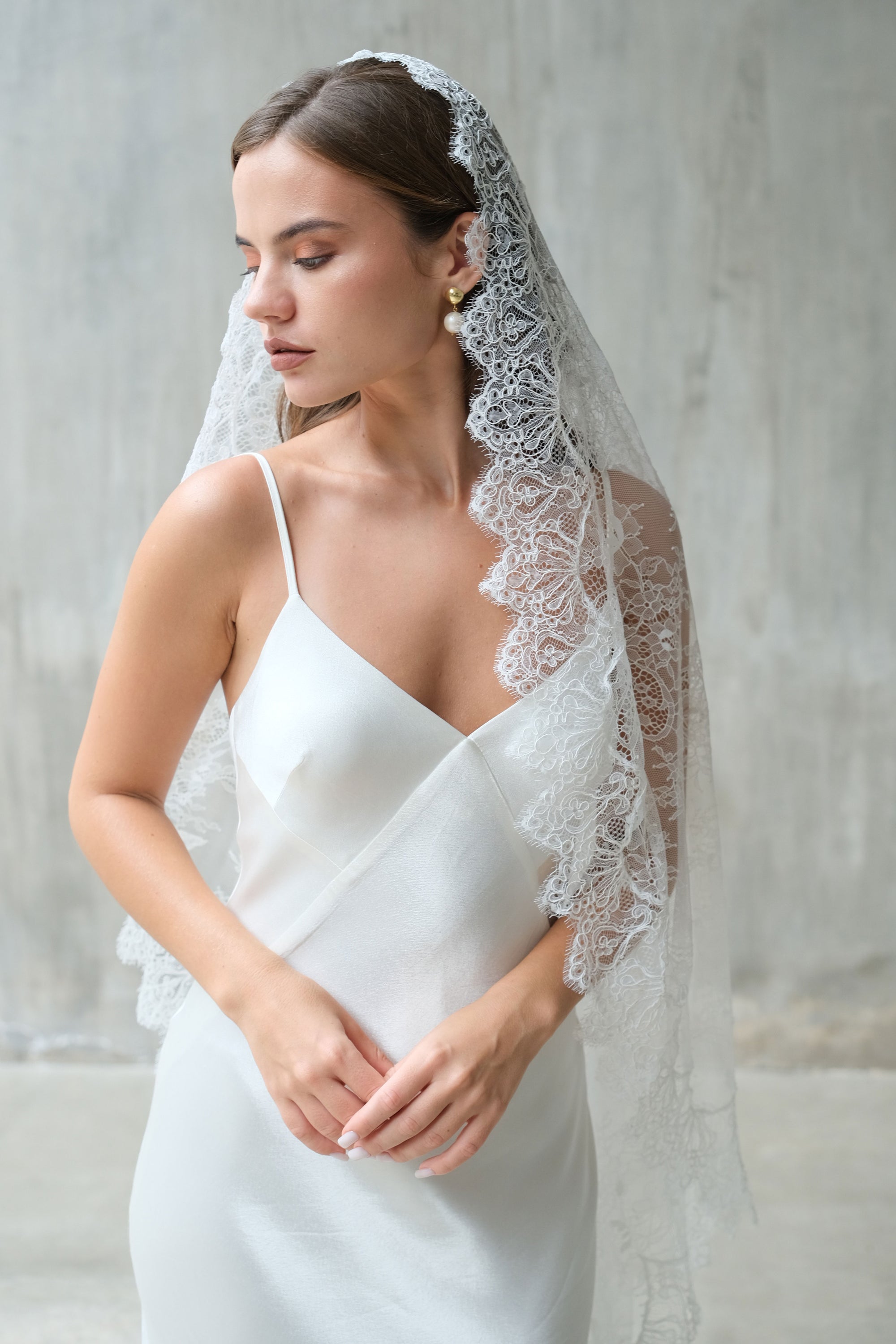Bride in profile wears a trditional style lace mantilla veil with scalloped lace edging