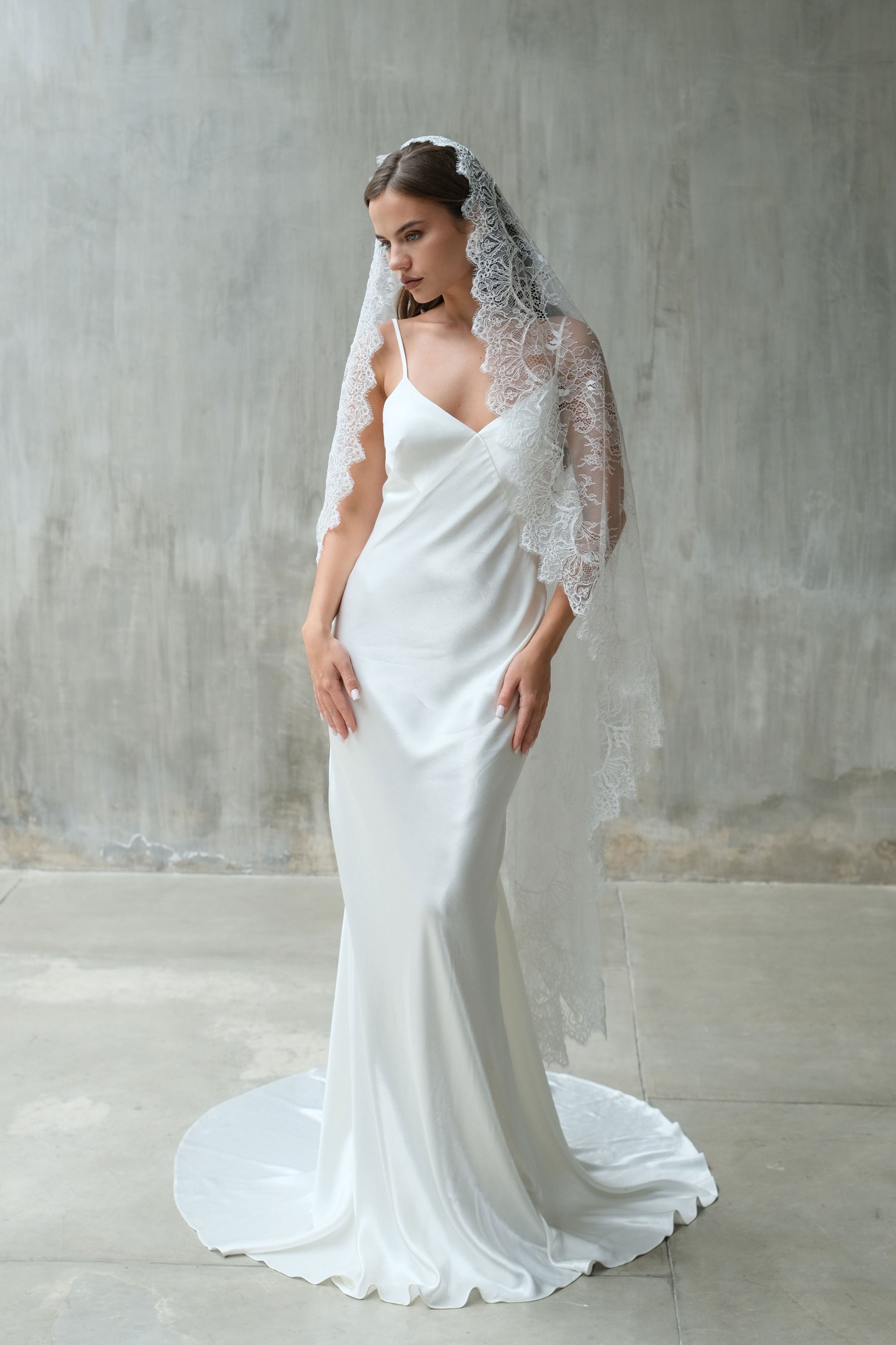 Full length front facing bride wears waltz length lace mantilla with scalloped edging