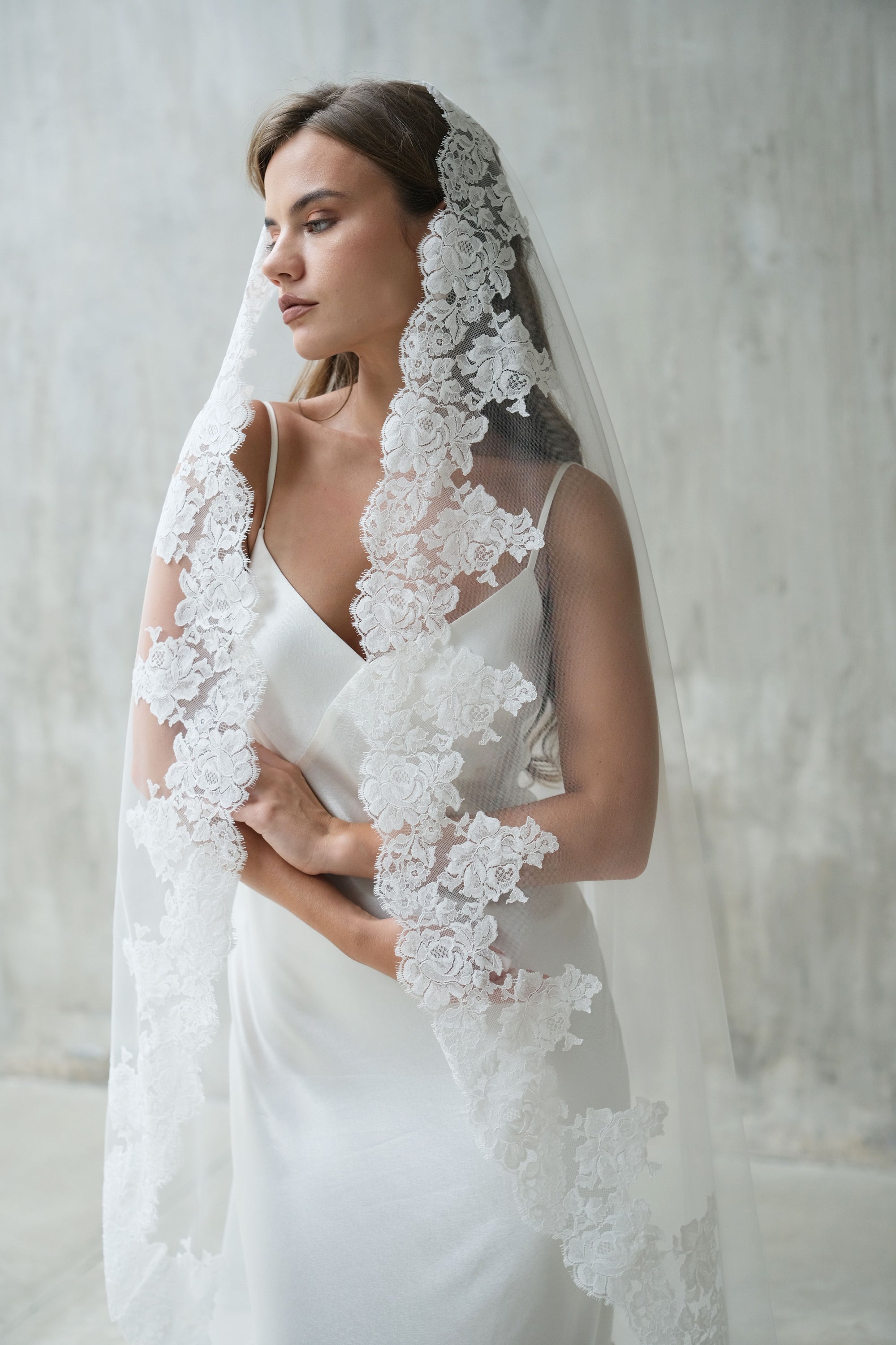 Model wears one-tier (mantilla) lace edged wedding veil