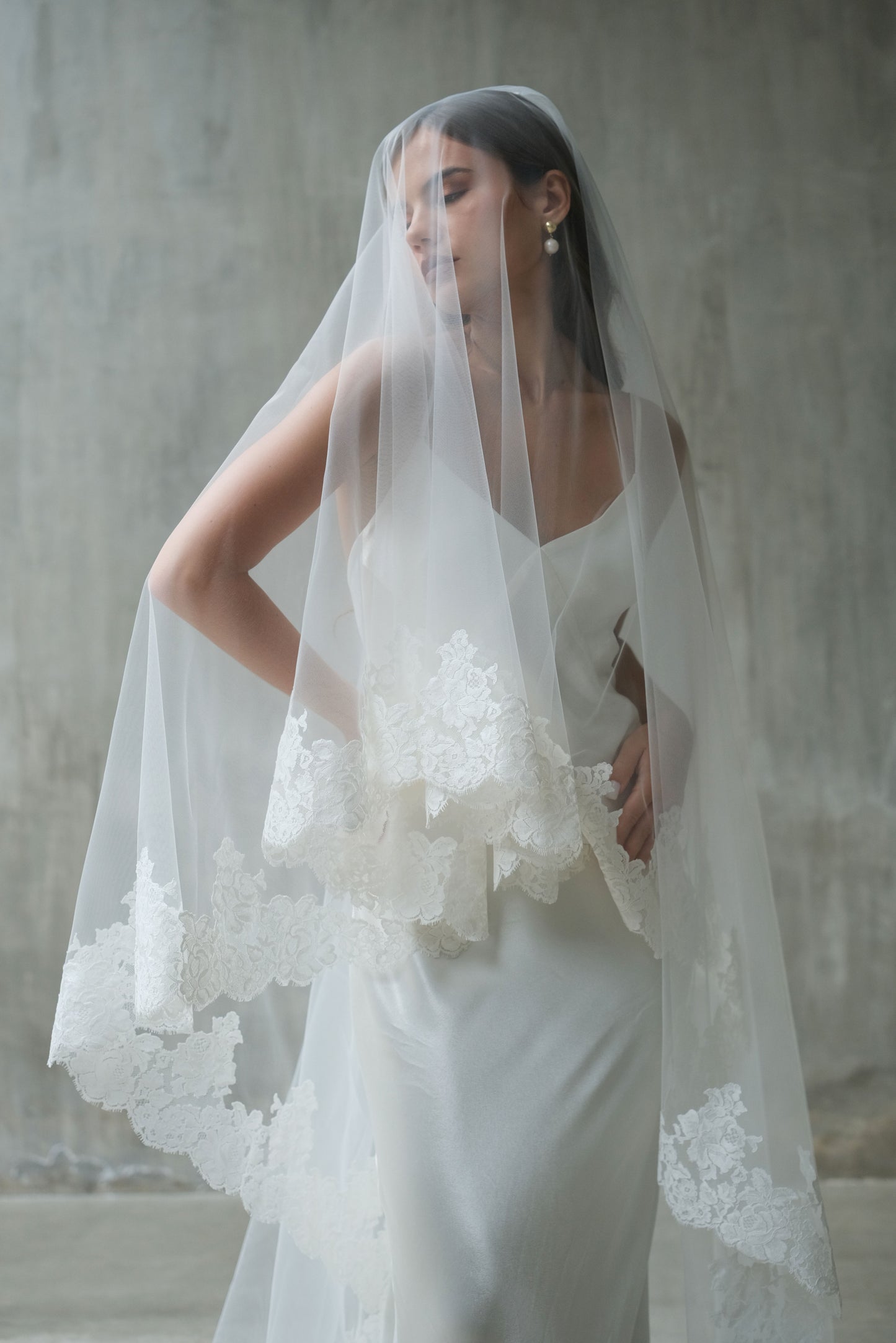 Half length shot of bride showing two tier veil, blusher down and trimmed with elaborate lace detail