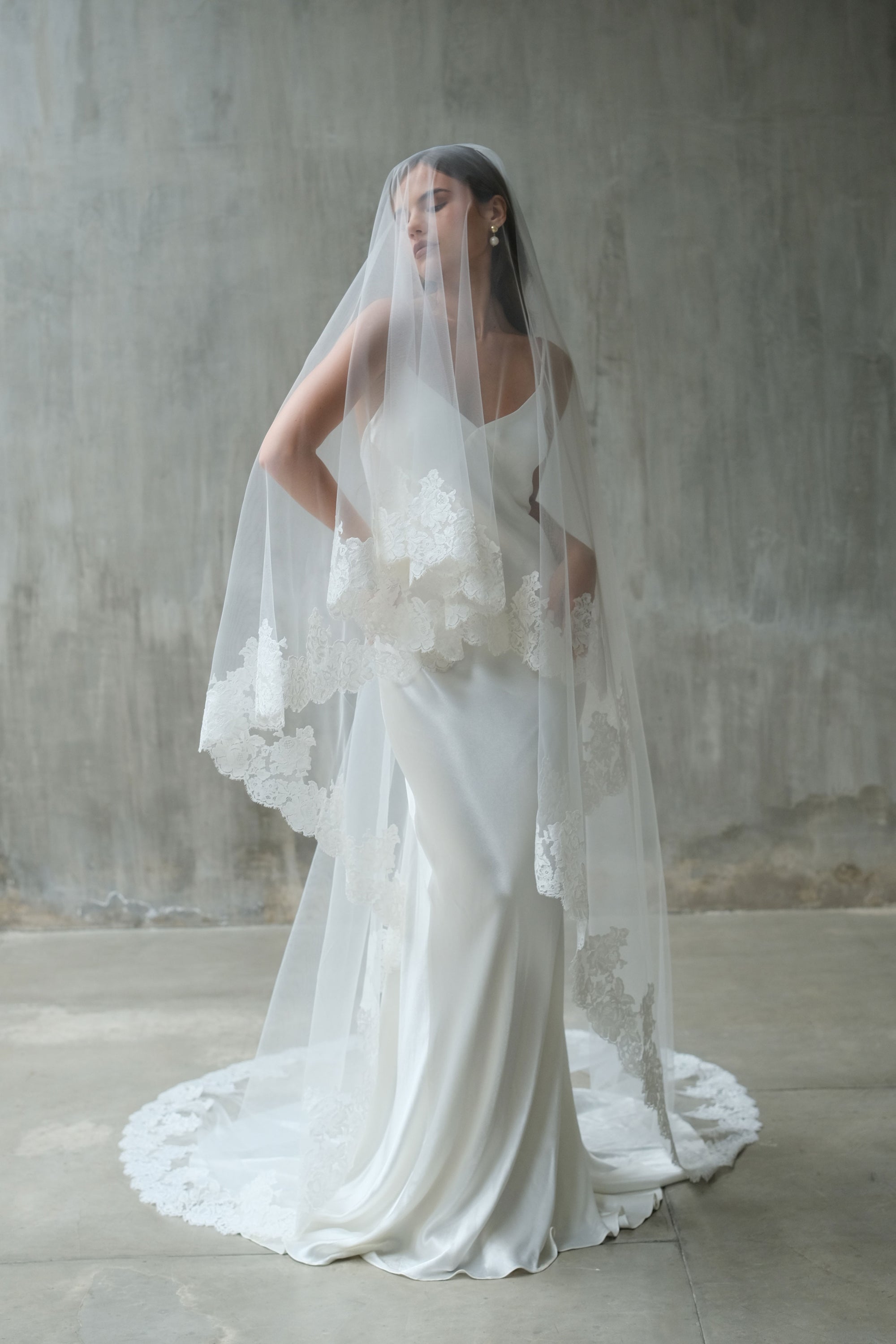 Full length front facing bride wears romantic lace-trimmed two tier, long wedding veil