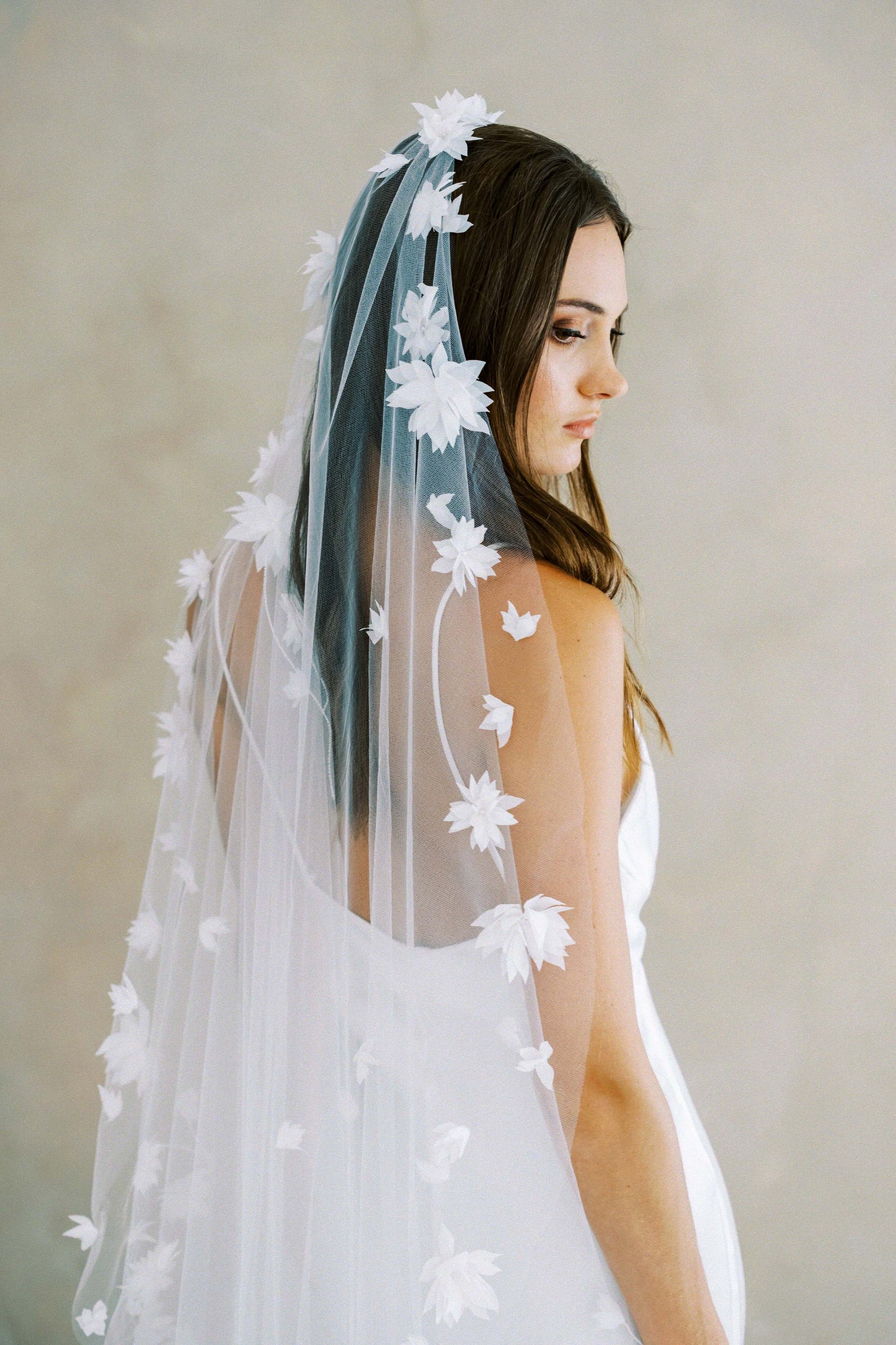 Bride models long, one tier veil scattered with 3-D fabric flowers
