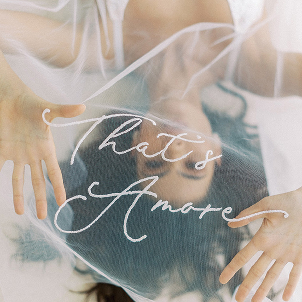 Bride holds up drop veil custom embroidered with romantic message