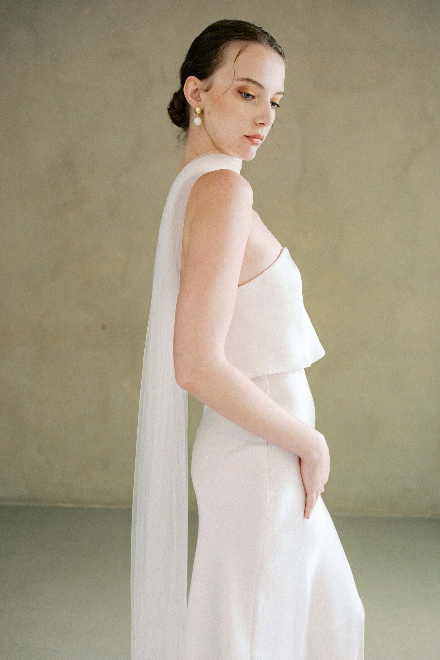 Half length shot of bride in profile modelling long soft tulle bridal scarf