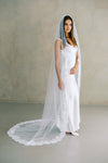Model wears a lace wedding veil, one tier veil with partial lace trim.