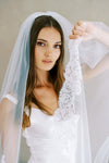 Model wears a lace wedding veil, one tier veil with partial lace trim.