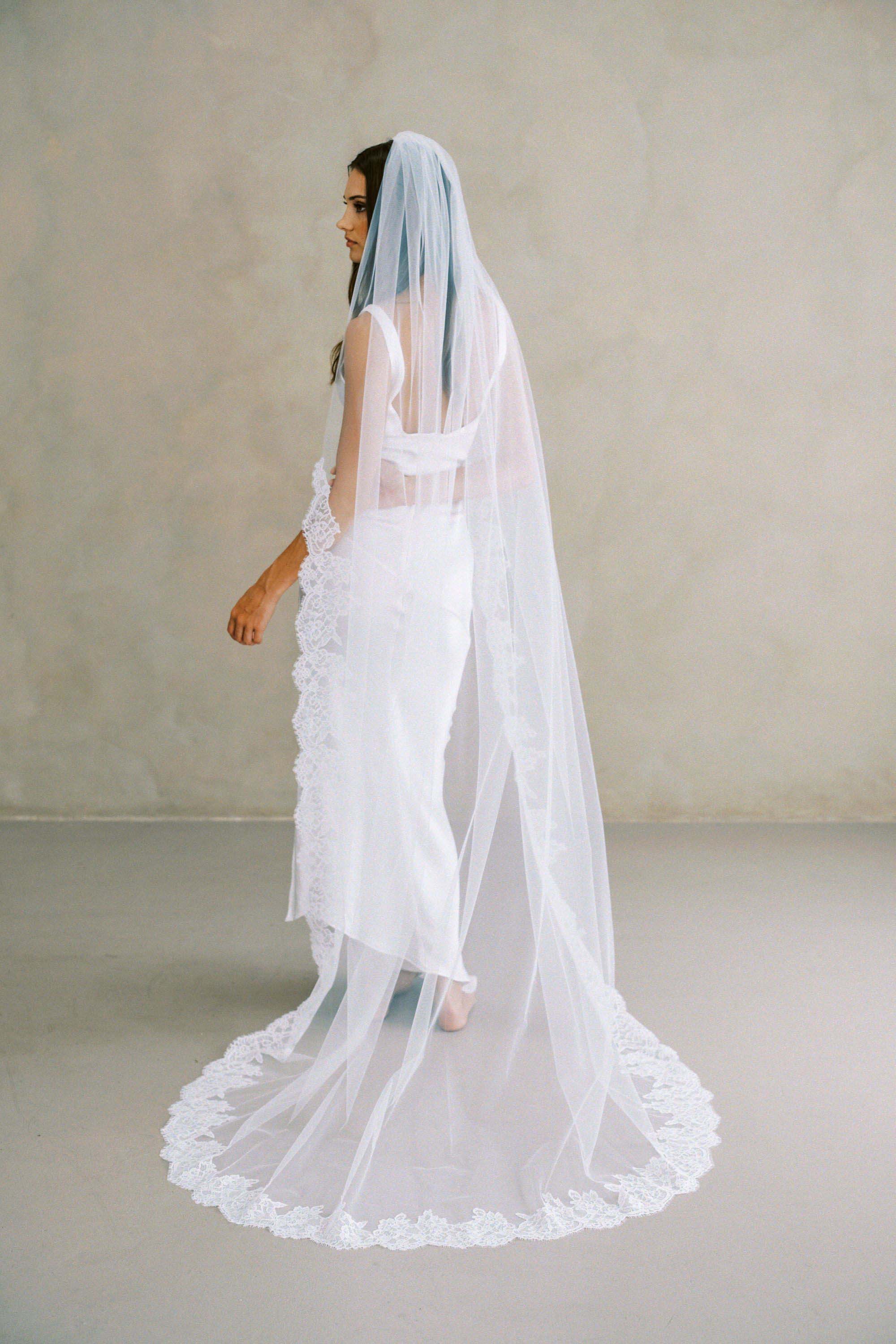 Model wears a lace wedding veil, one tier veil with partial lace trim.