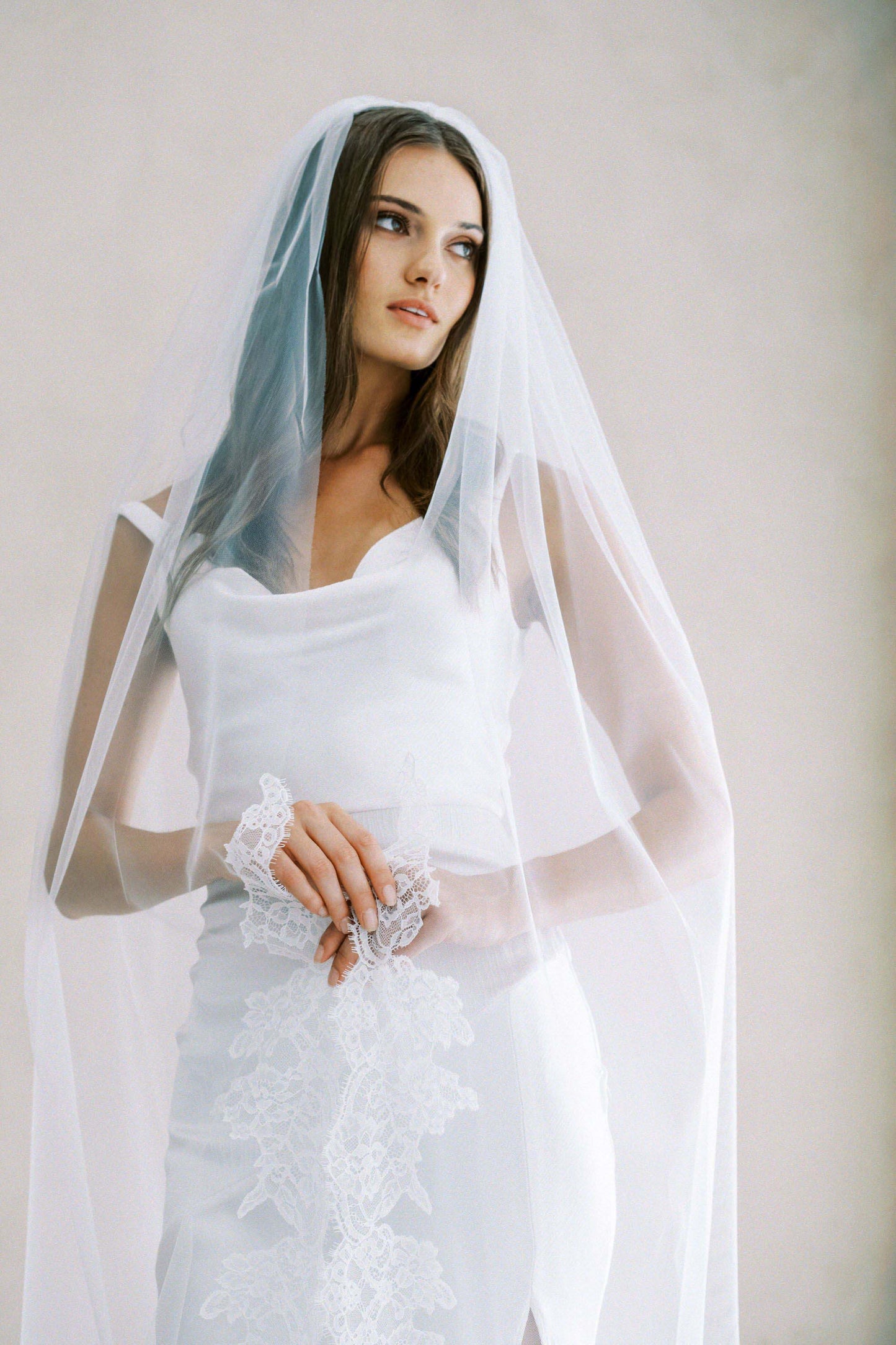 Model wears a lace wedding veil, one tier veil with partial lace trim.