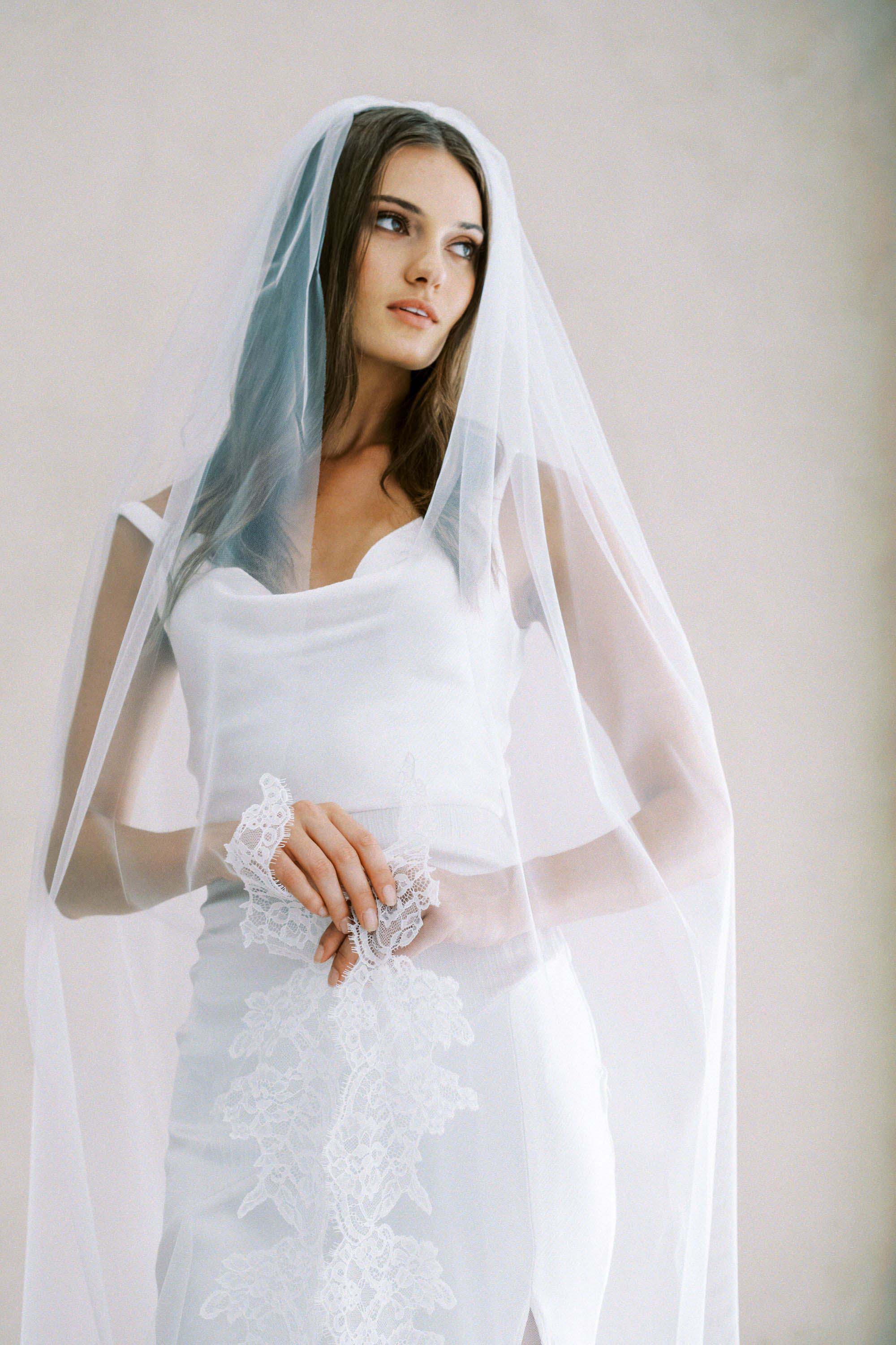 Model wears a lace wedding veil, one tier veil with partial lace trim.