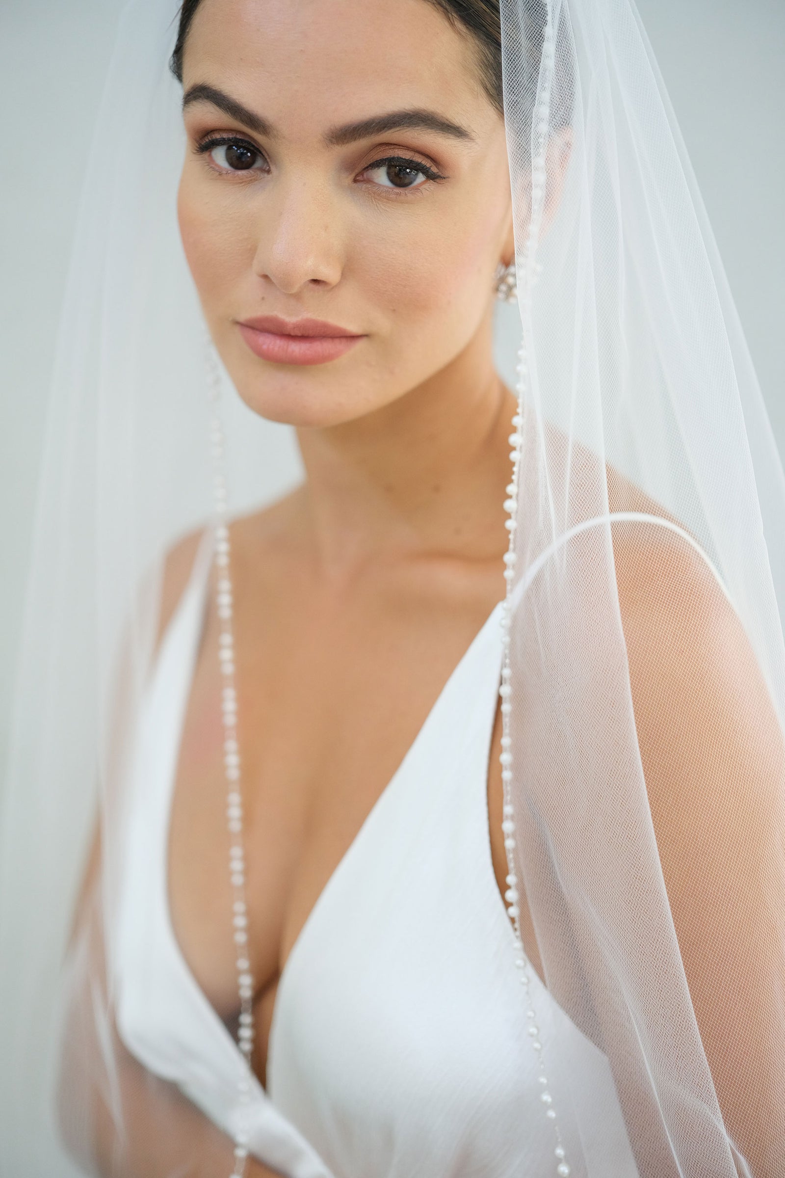 model wears a one-tier wedding veil, veil with pearls on the edge