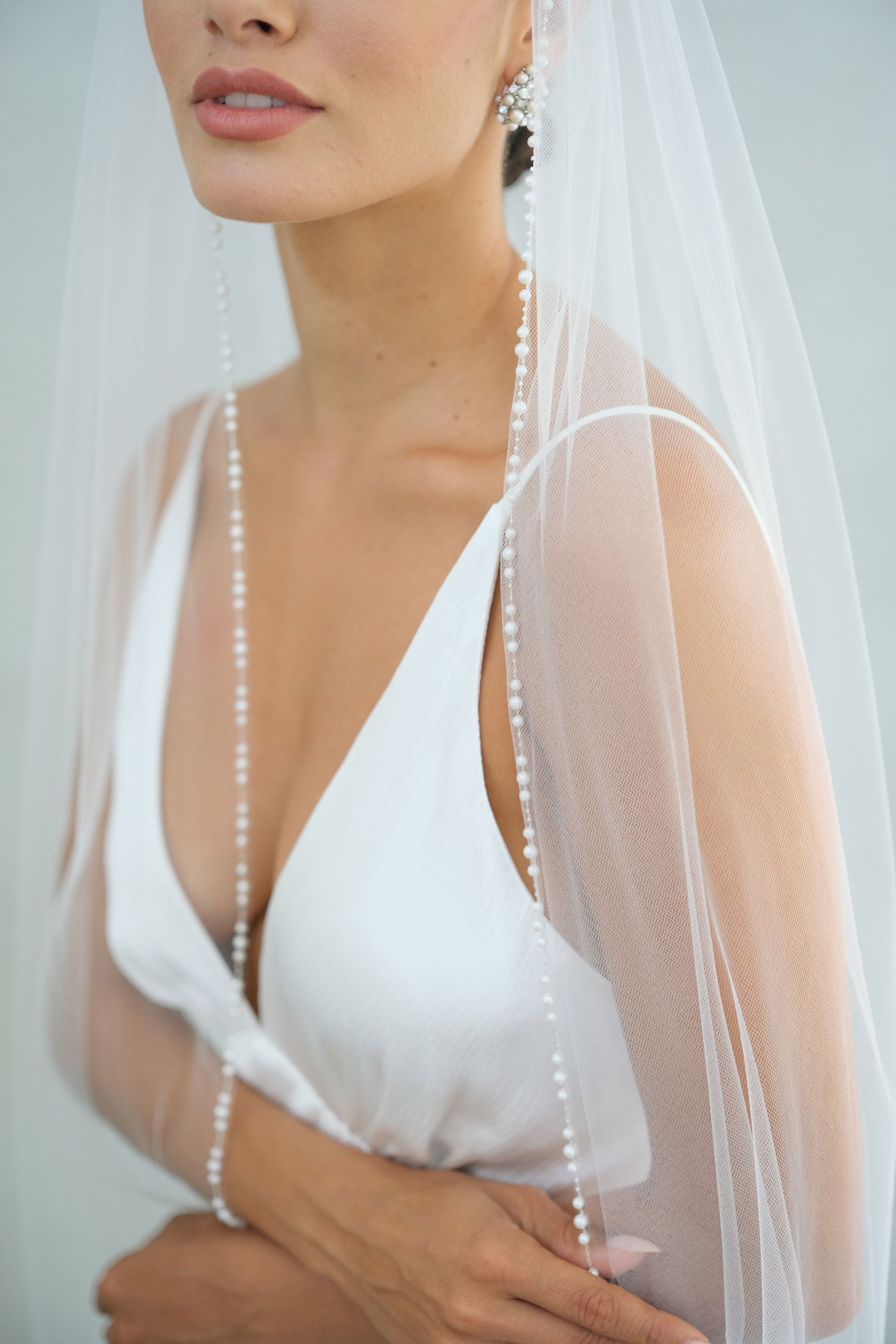 model wears a one-tier wedding veil, veil with pearls on the edge