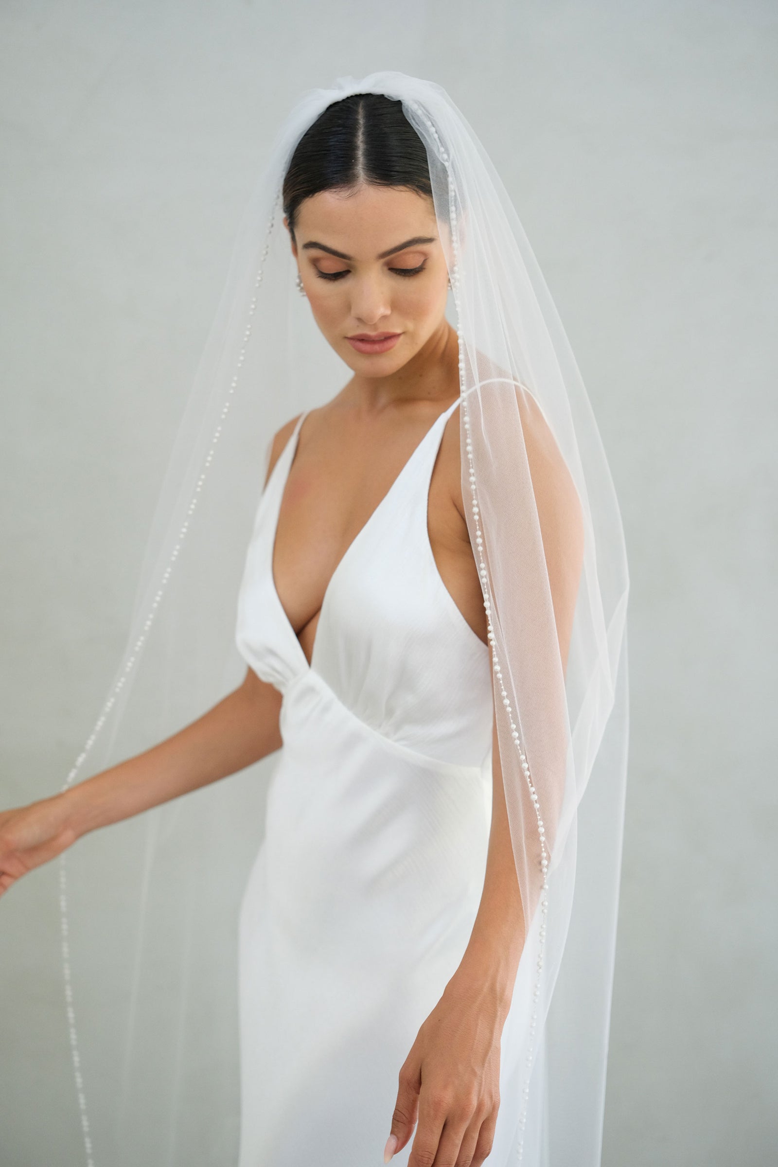 model wears a one-tier wedding veil, veil with pearls on the edge
