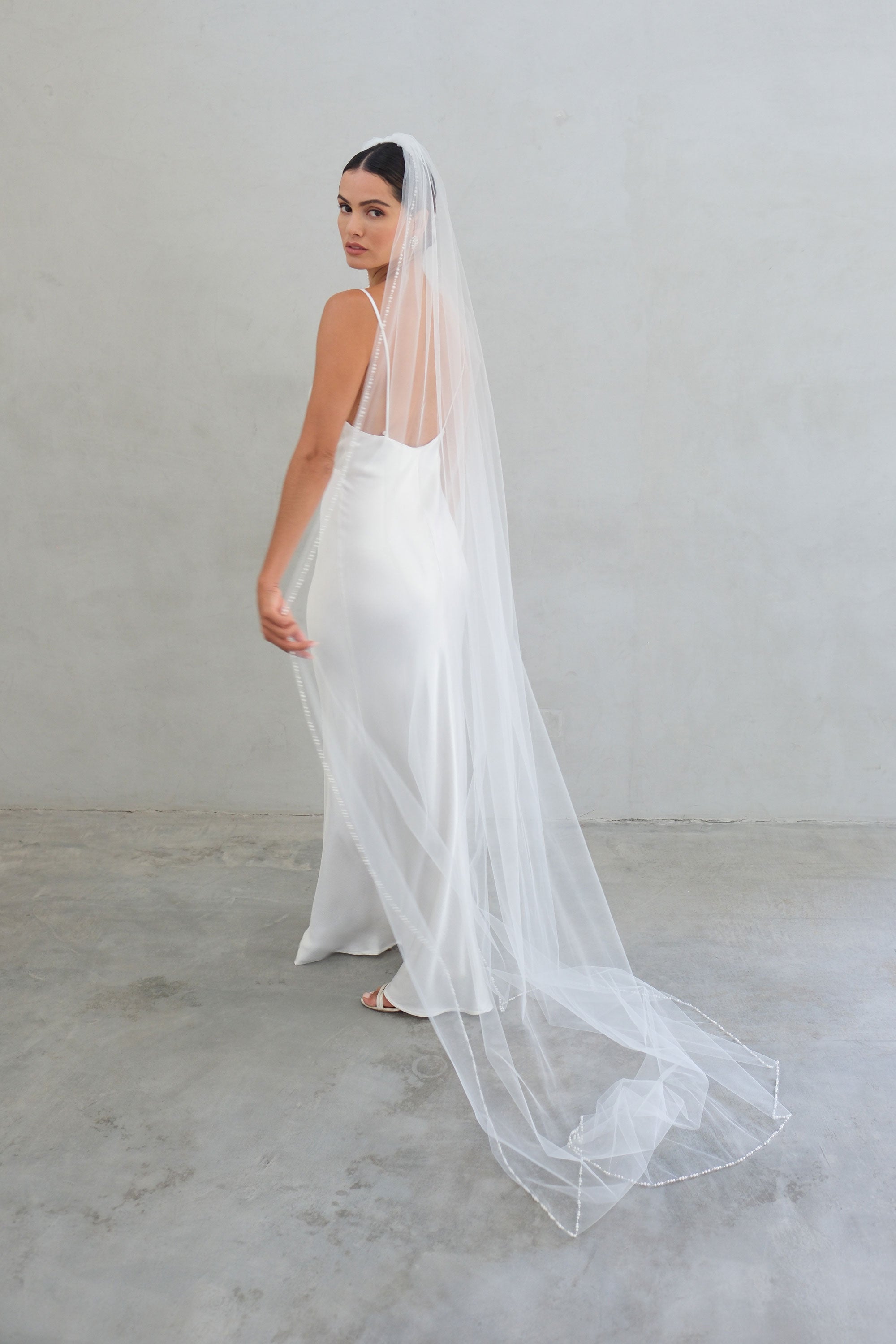 model wears a one-tier wedding veil, veil with pearls on the edge