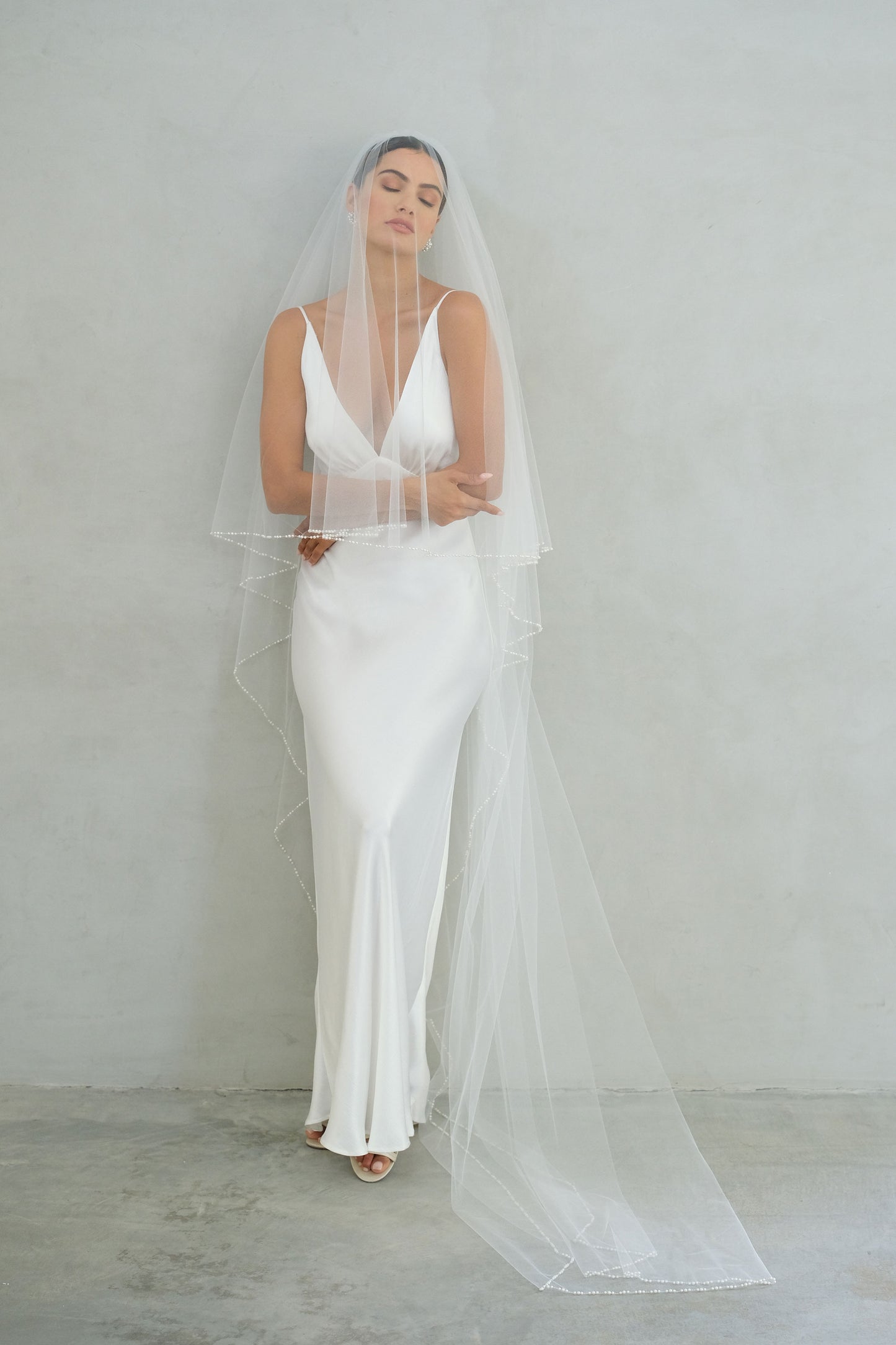 model wears a two-tier wedding veil, drop veil with pearls on the edge