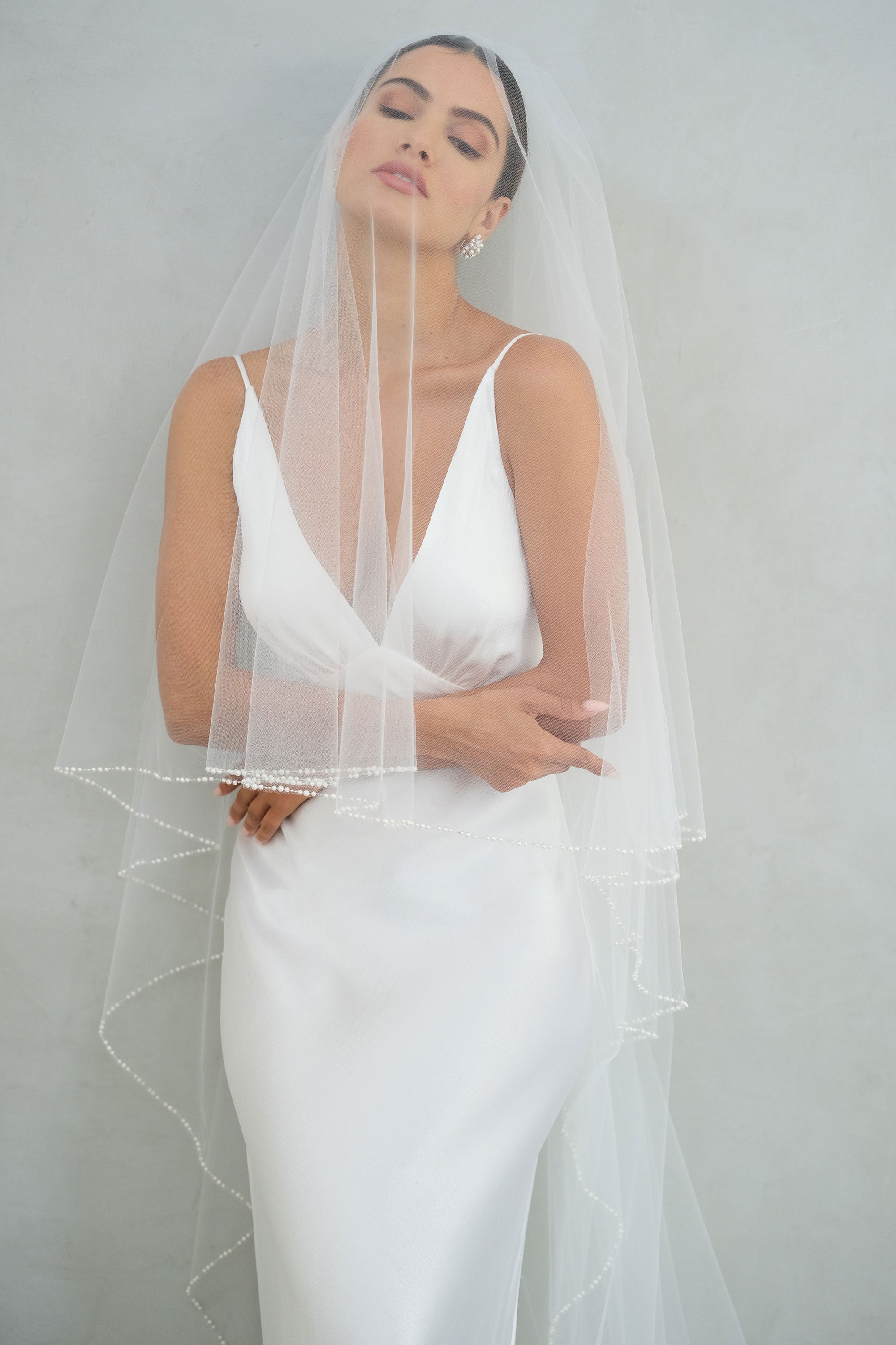 model wears a two-tier wedding veil, drop veil with pearls on the edge