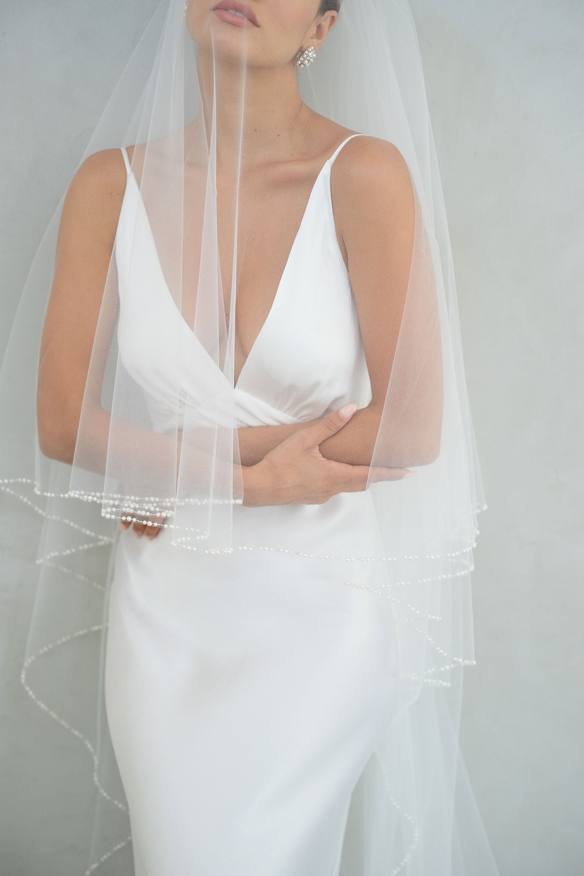 model wears a two-tier wedding veil, drop veil with pearls on the edge