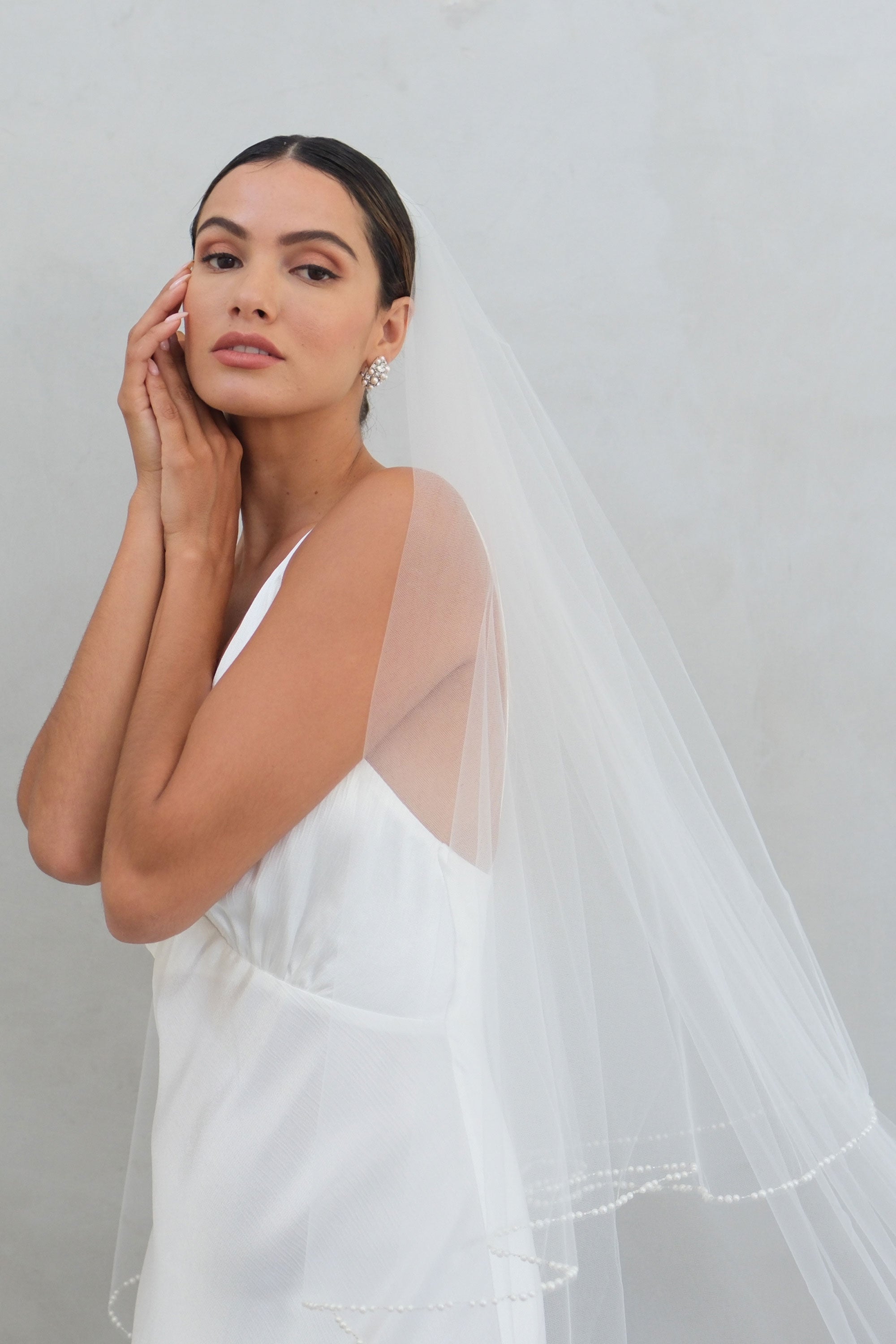 model wears a two-tier wedding veil, drop veil with pearls on the edge