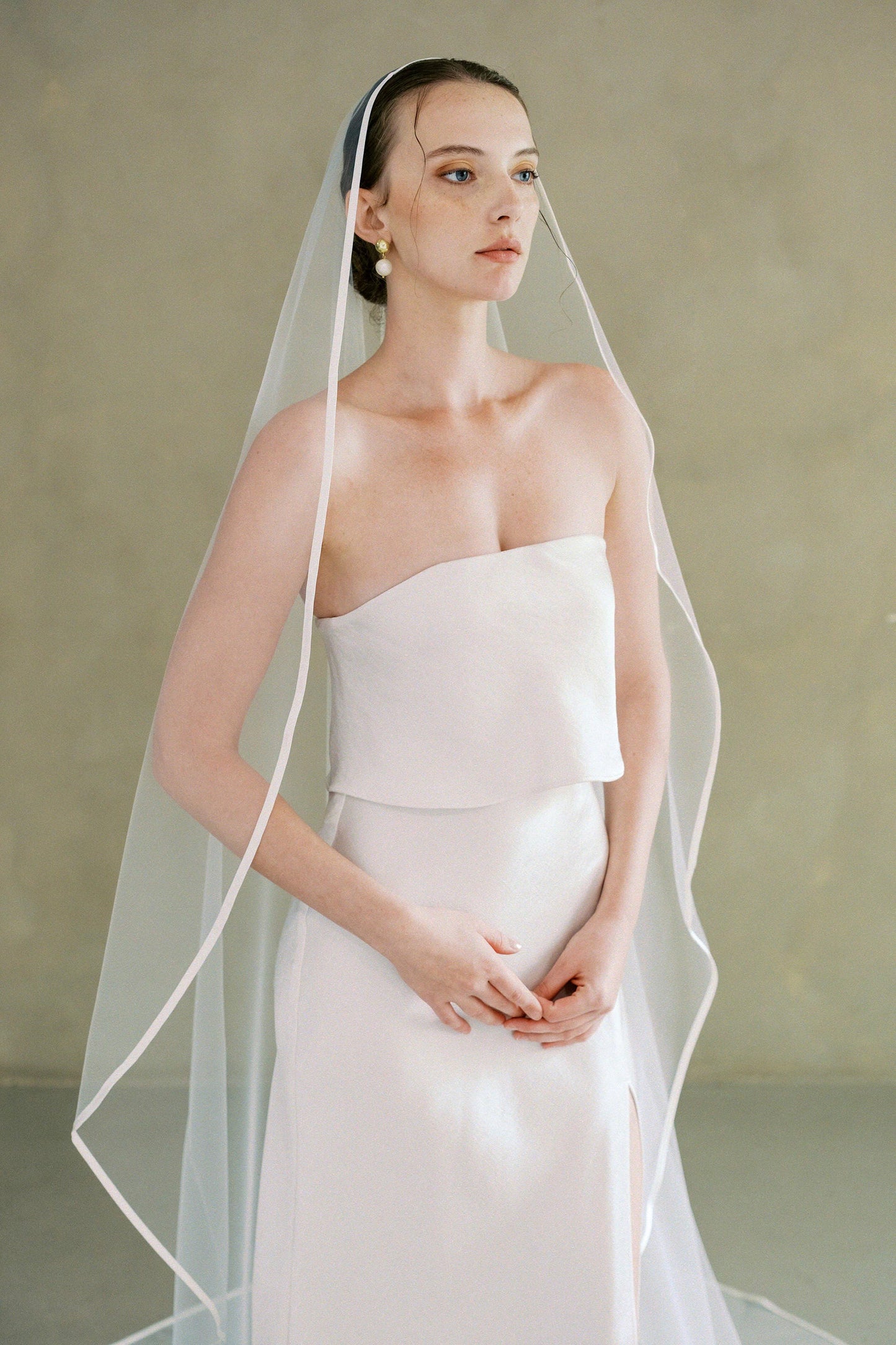 Model wears one-tier satin edge wedding veil