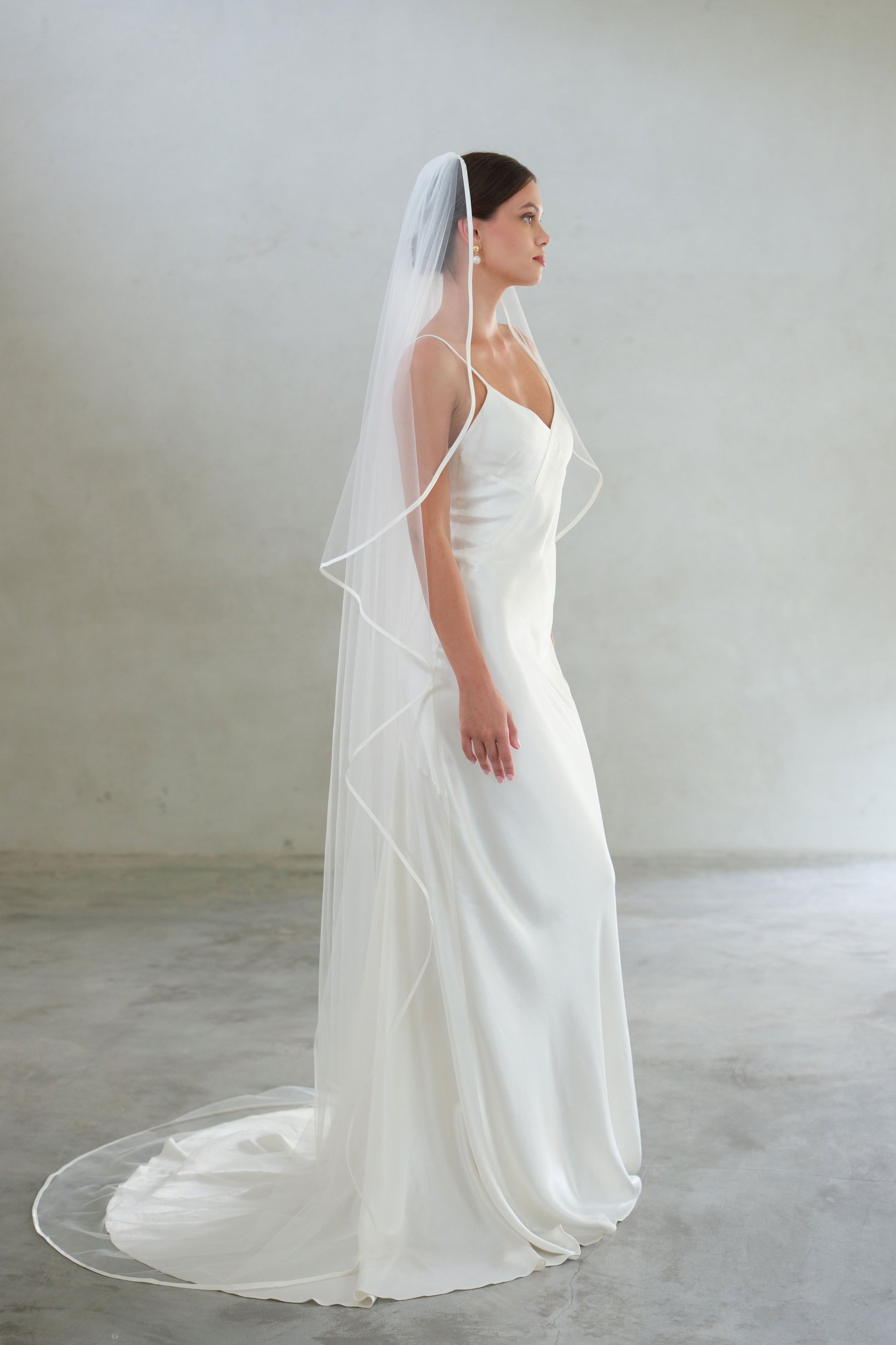 Full length side view of long wedding veil gathered at the comb and edged with satin ribbon