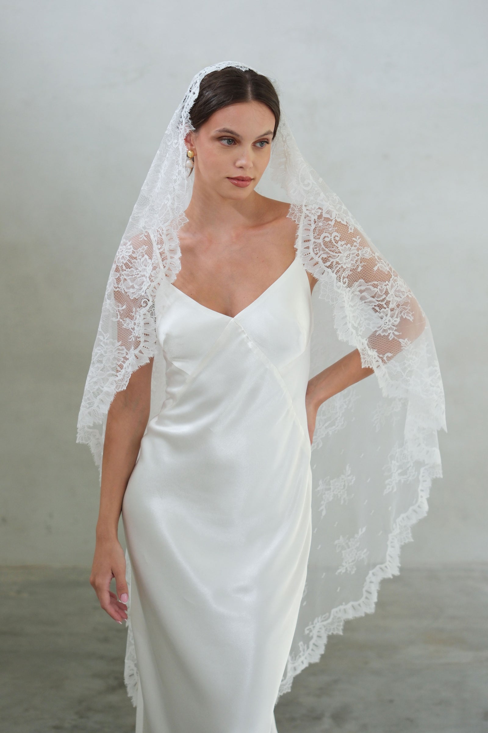 Front facing bride wears full lace mantilla with delicate scallop trim