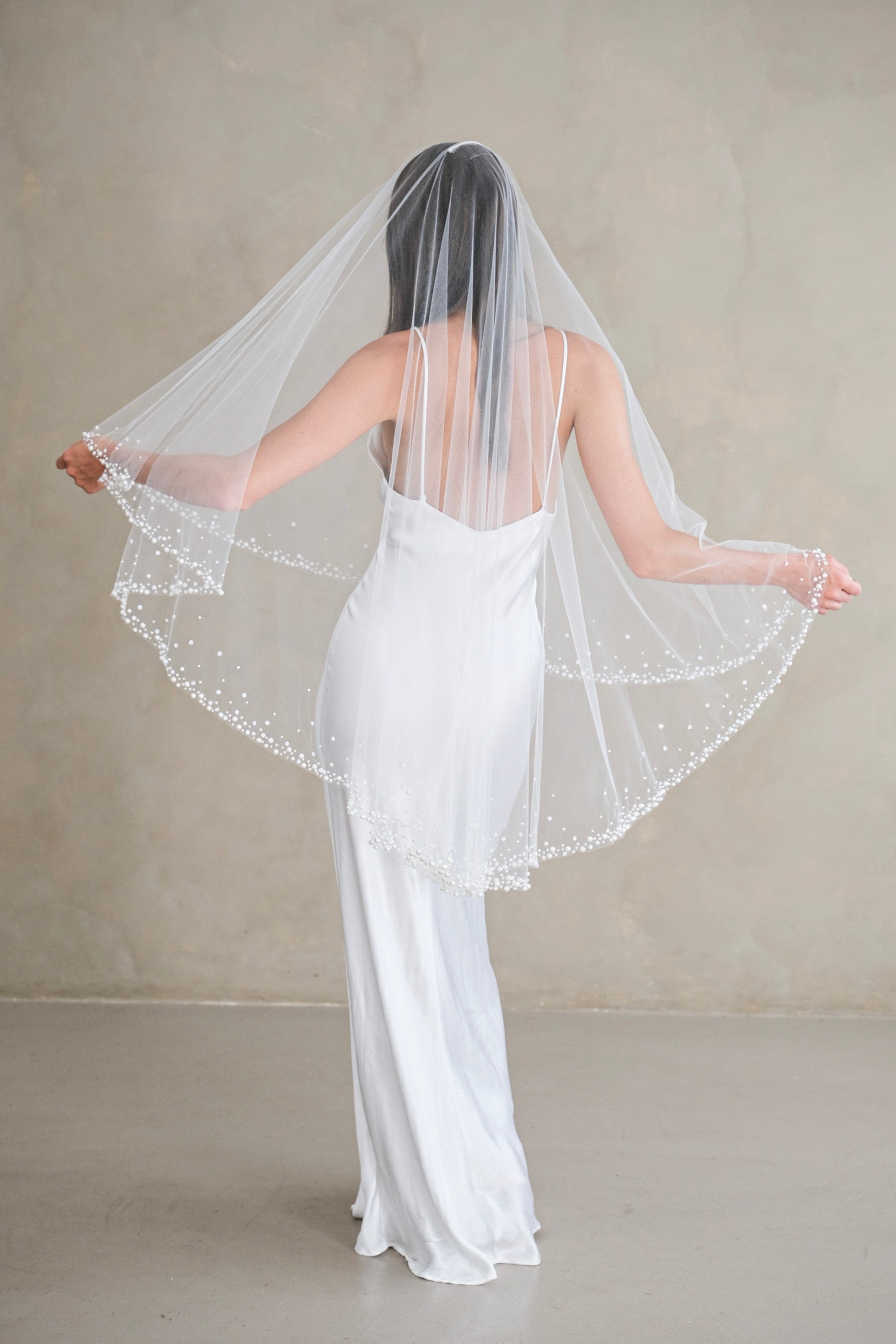 Model wears a two-tier wedding veil, drop veil with pearls and sequins