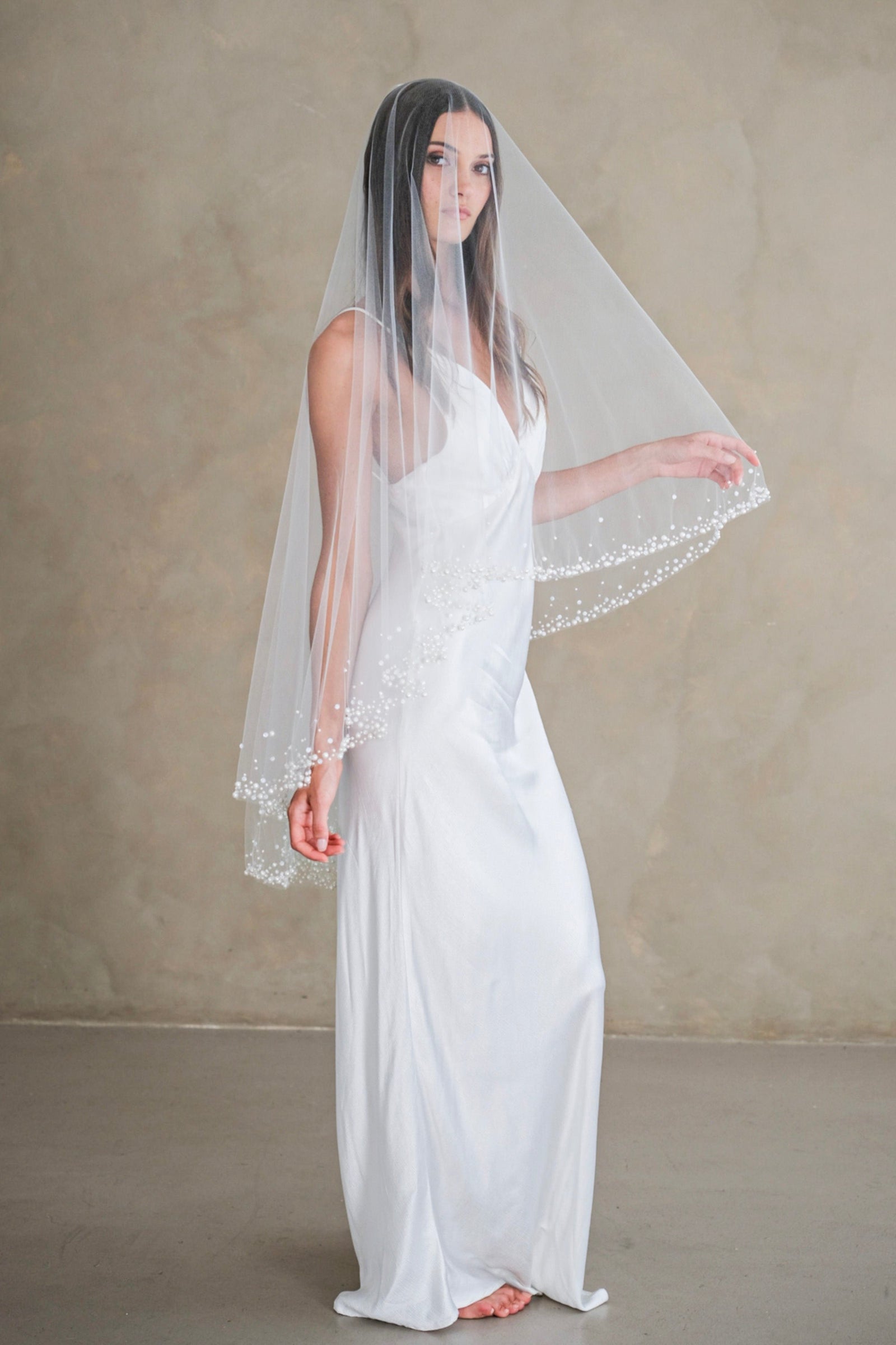 Model wears a two-tier wedding veil, drop veil with pearls and sequins