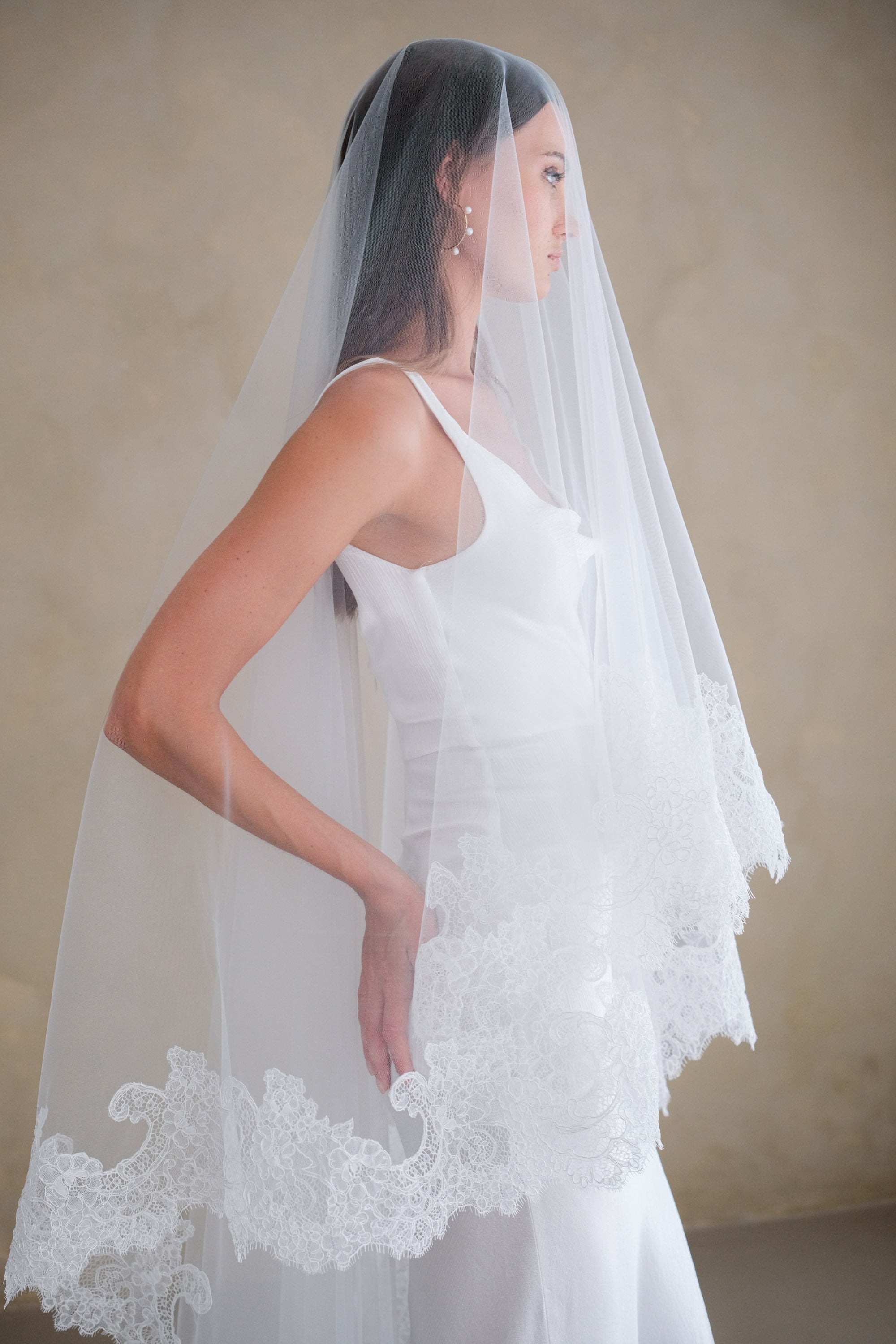 Model wears a mantilla lace wedding veil, drop veil with lace trim.
