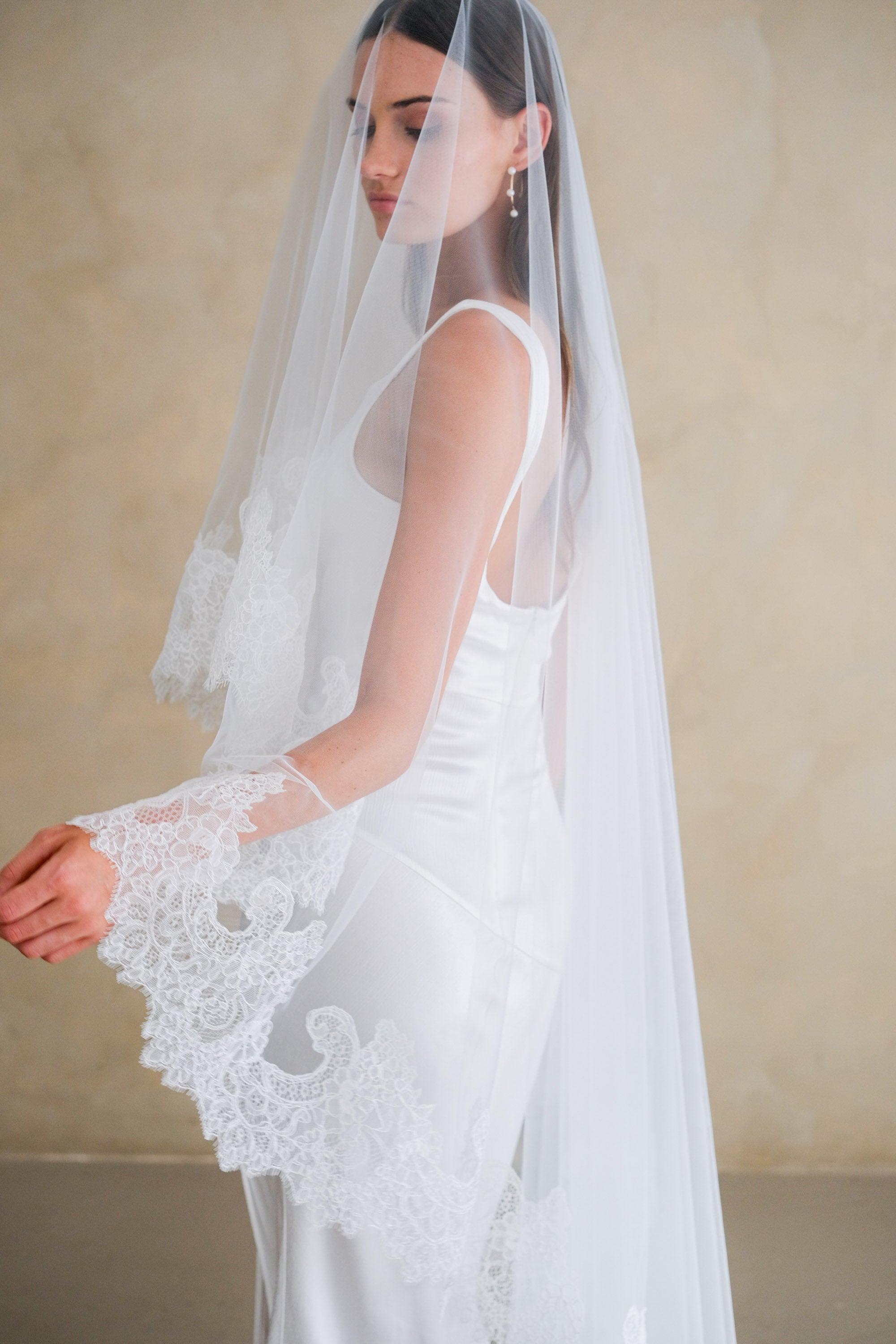 Model wears a mantilla lace wedding veil, drop veil with lace trim.