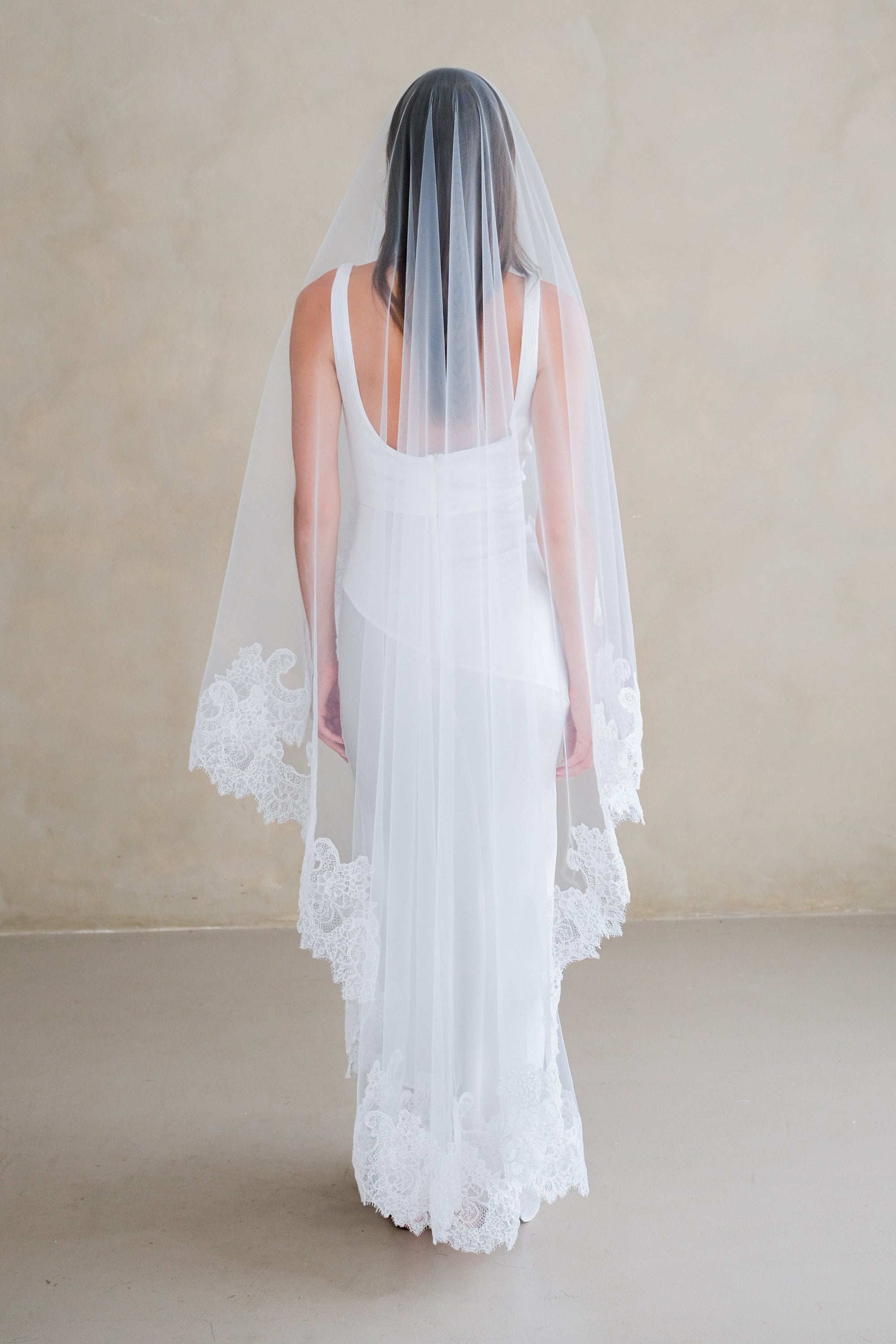 Model wears a mantilla lace wedding veil, drop veil with lace trim.