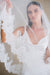 Model wears a lace wedding veil, drop veil with lace trim.