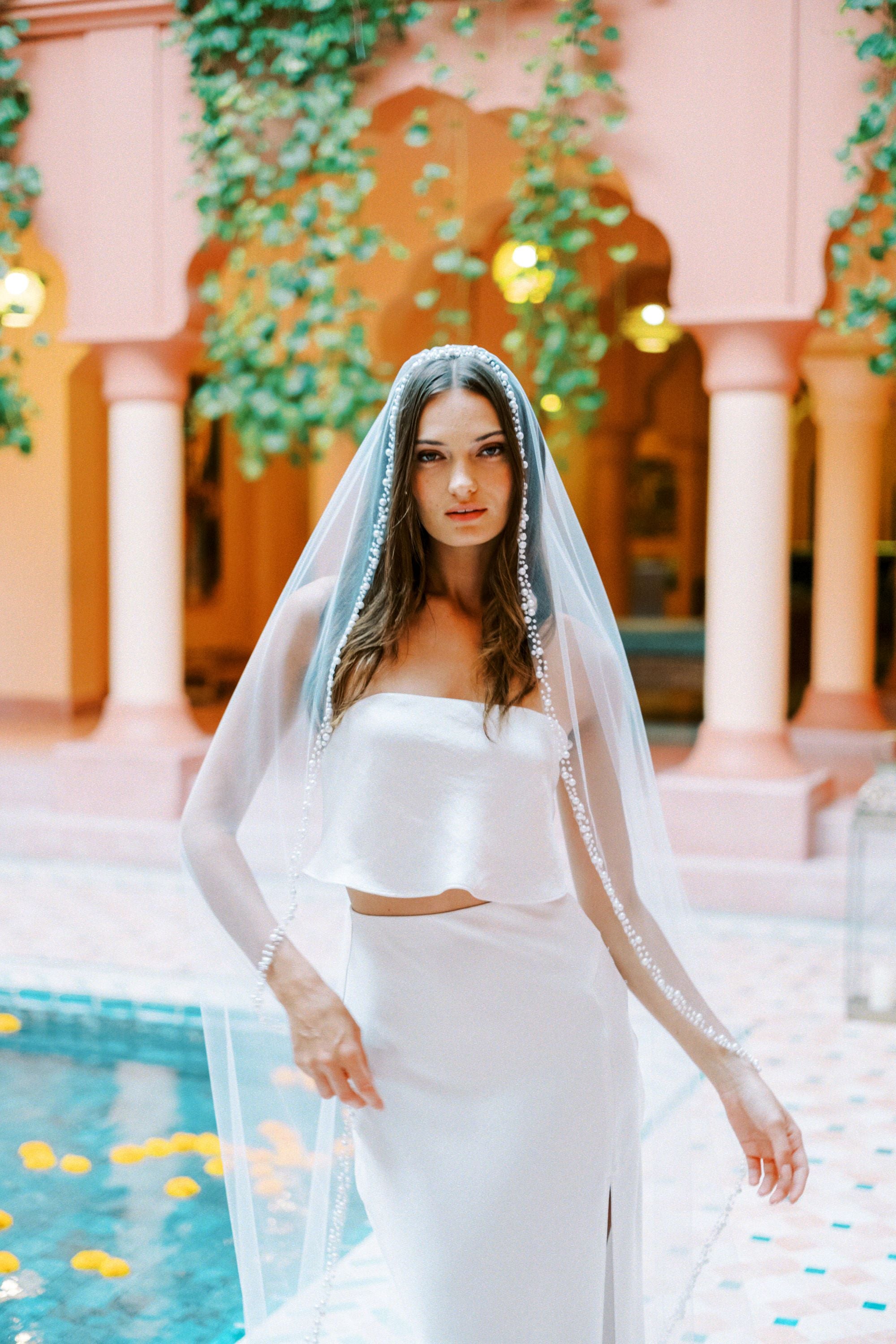 Model wears a pearl wedding veil, one tier veil with pearls.