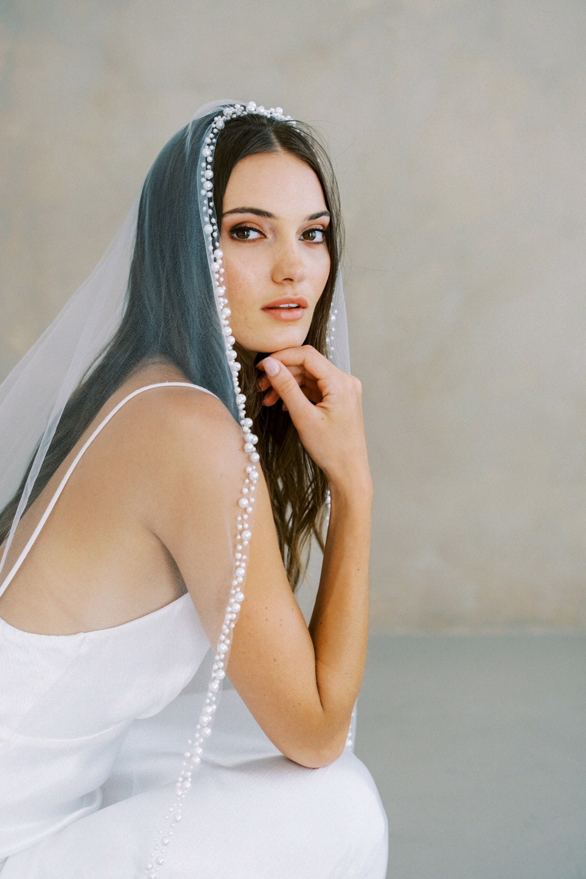Model wears a pearl wedding veil, one tier veil with pearls.