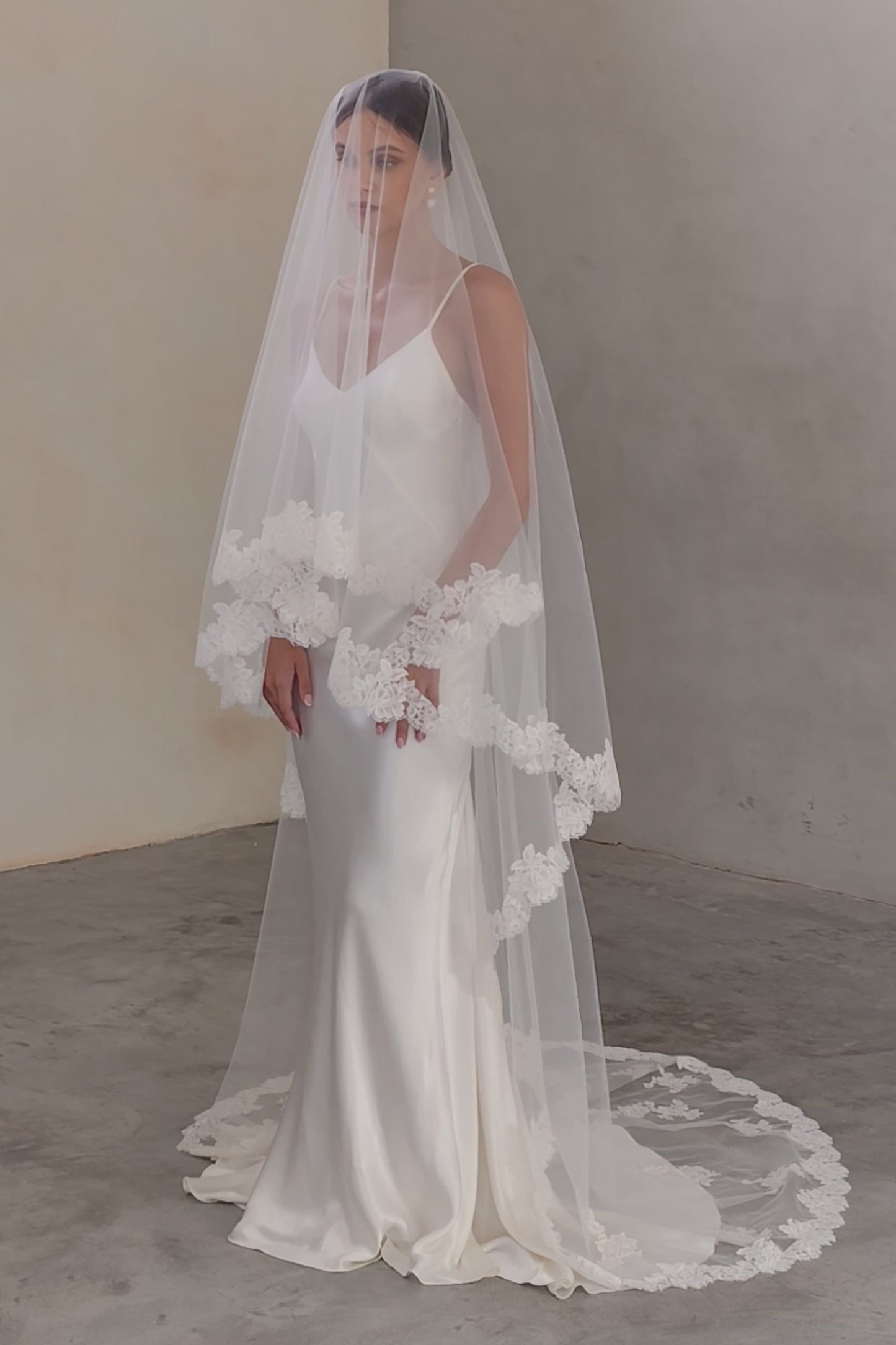 Full length view of bride wearing two-tiered veil (with blusher) featuring floral lace edging and appliques scattered around train